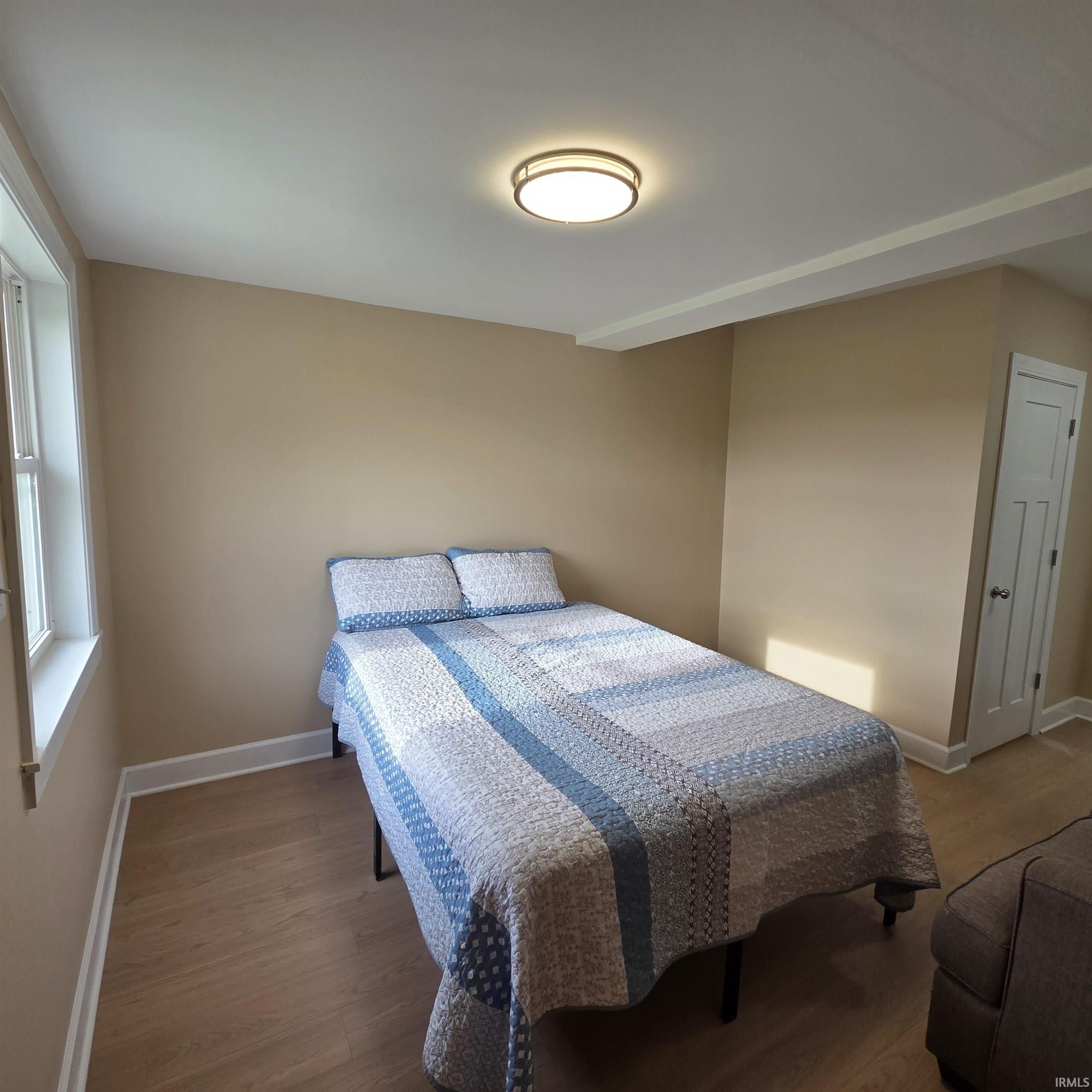 Bedroom featuring vinyl plank flooring, neutral wall tones, and white trim