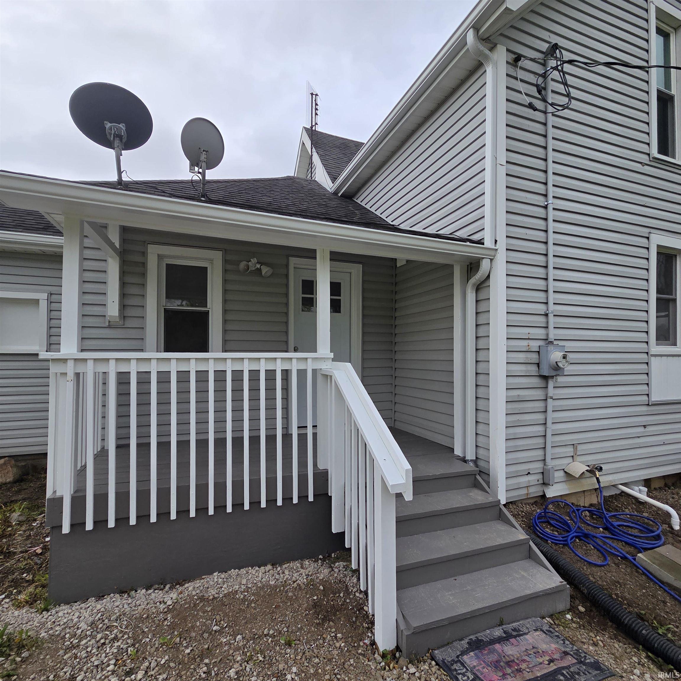 Front porch with gray vinyl siding, white railing, and a matching gray entry door