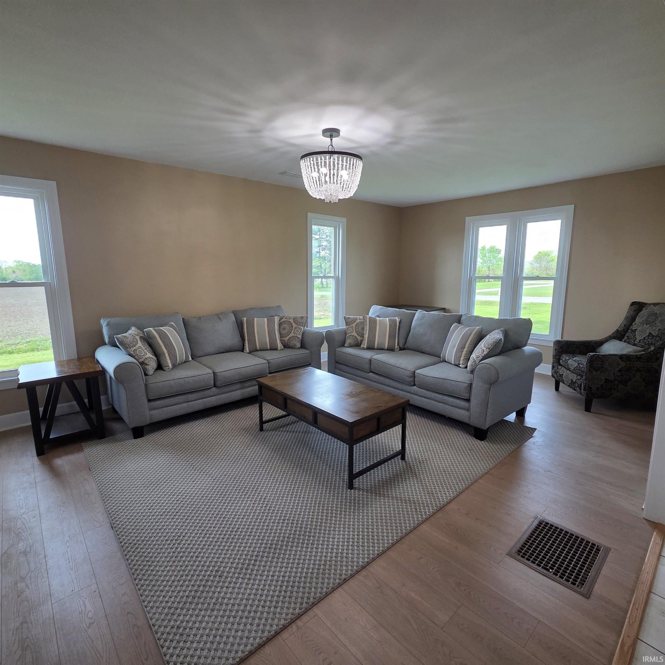 Spacious room featuring light-toned walls, wood-finish flooring, and multiple windows