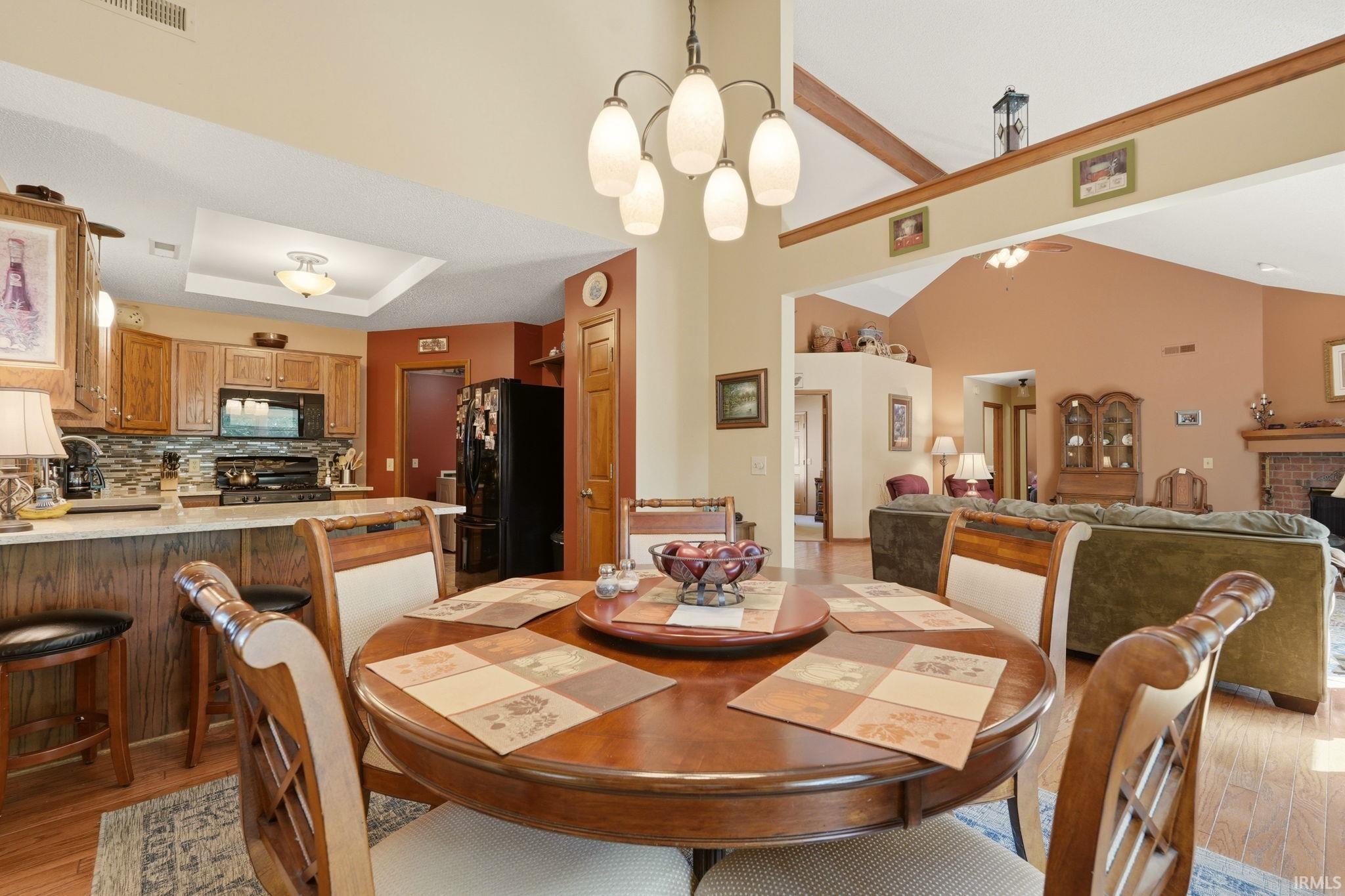 Dining area with wood-finish flooring, featuring a tiered chandelier and vaulted ceilings
