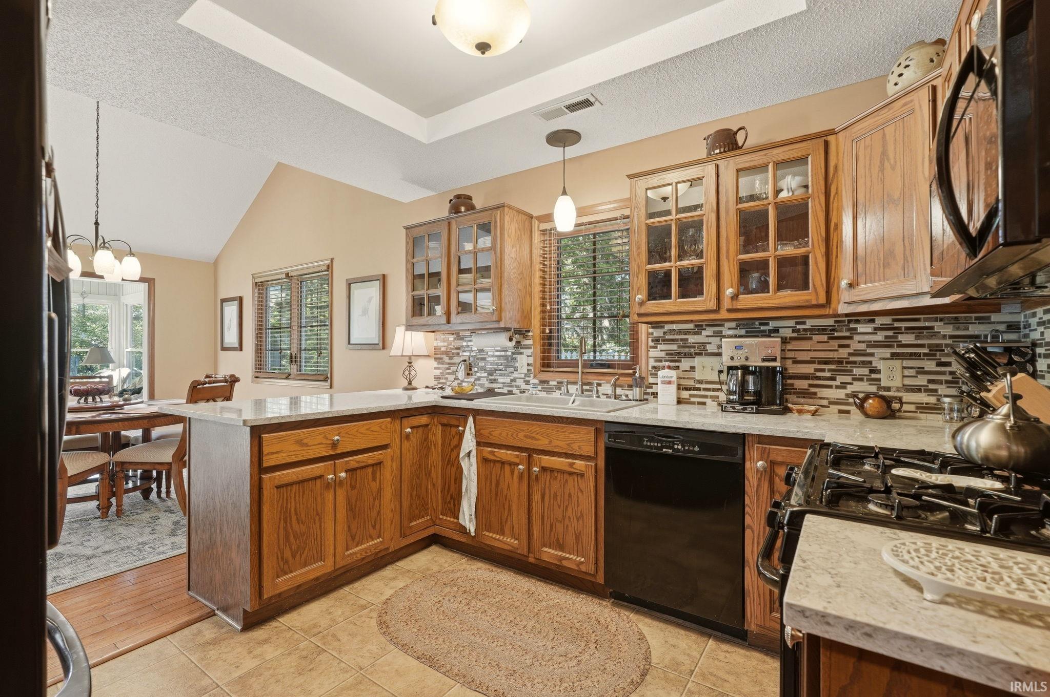 Kitchen featuring wood cabinetry, stone countertops, a mosaic tile backsplash, and stainless steel sink