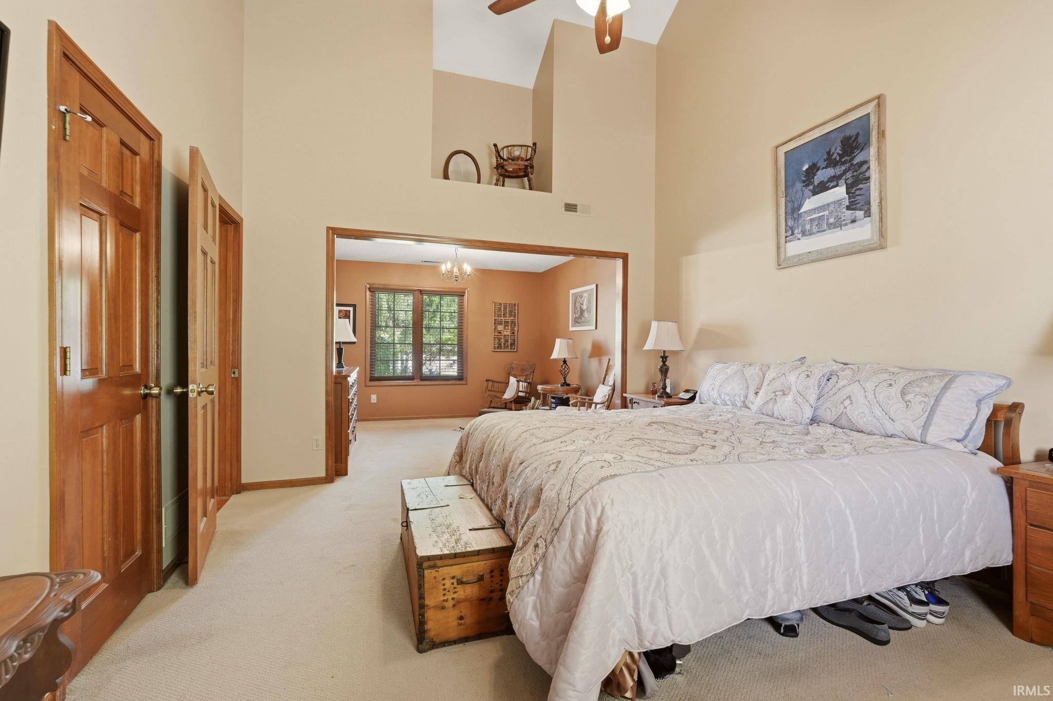 Room featuring a vaulted ceiling with a ceiling fan, a private entryway with two paneled doors, and an arched doorway opening to an additional room
