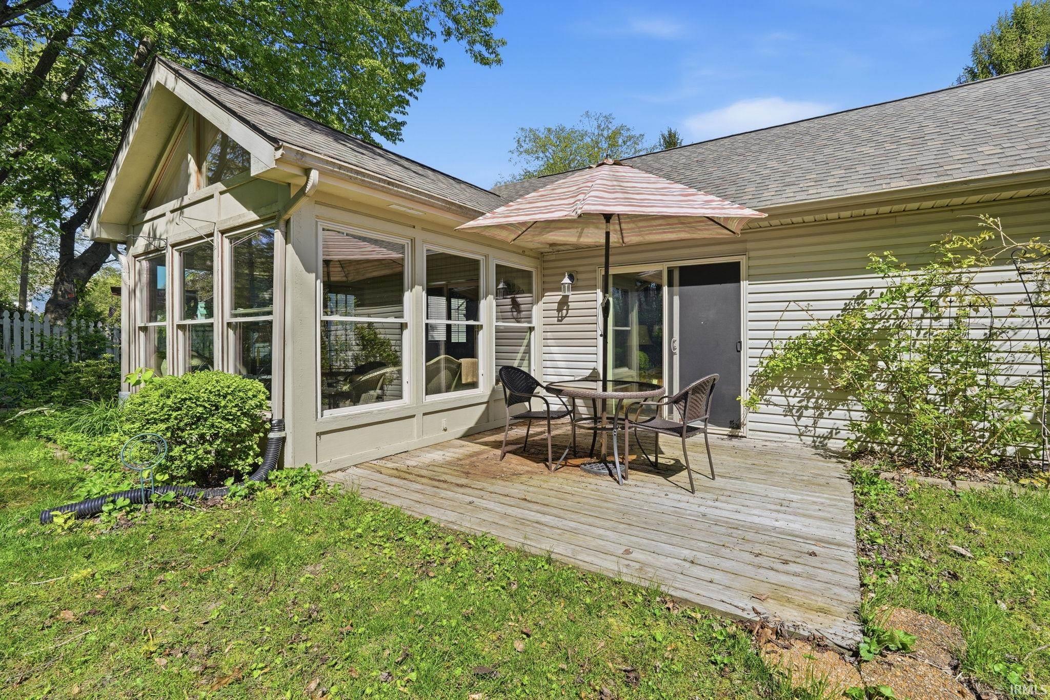 Sunroom with multiple large windows and an angled roofline, featuring a sliding glass door opening onto a wood deck