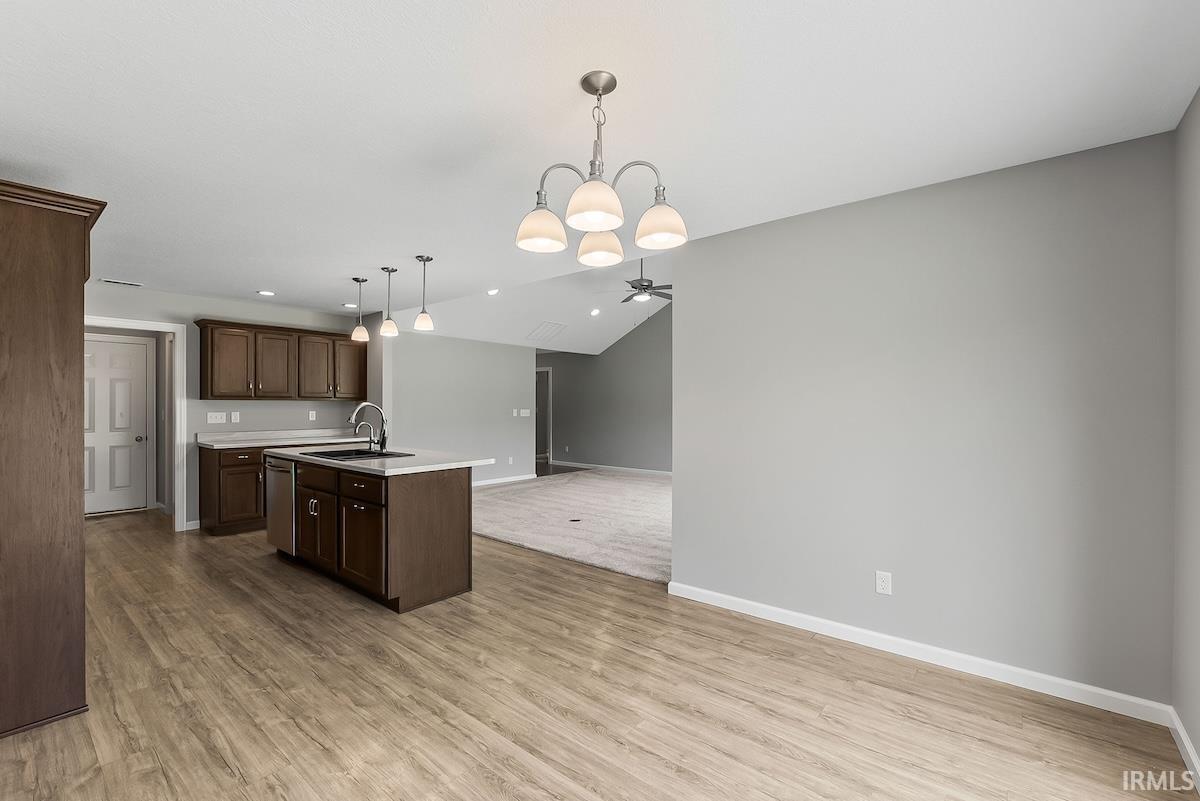 Kitchen island with integrated sink and dishwasher, featuring wood-finish cabinetry and light-toned countertops