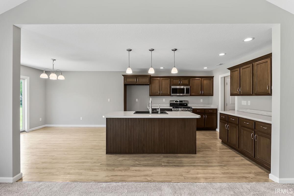 Kitchen featuring dark wood-finish cabinetry, light countertops, and a central island with pendant lighting