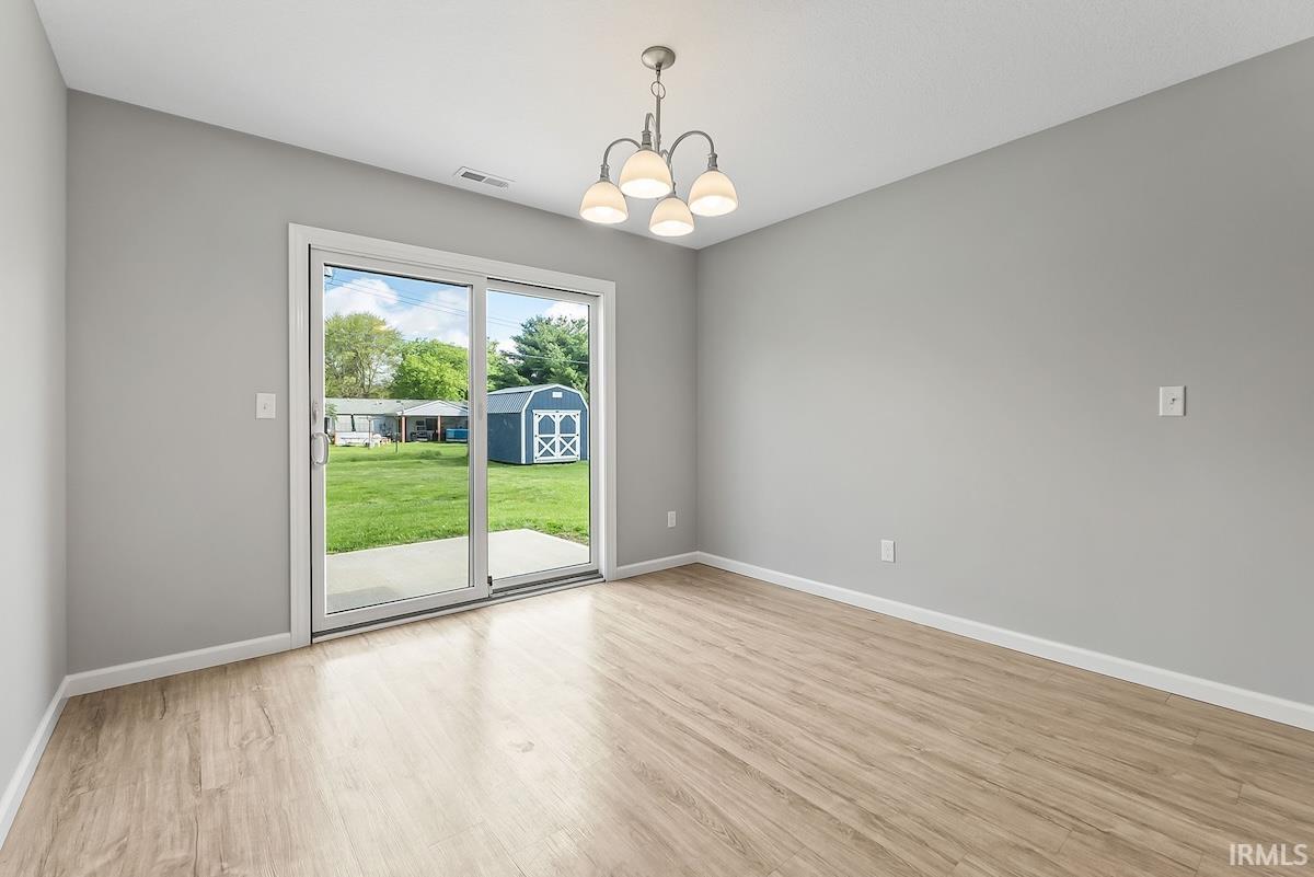 Sliding glass door opening to a concrete patio and a grassy backyard with a blue storage shed
