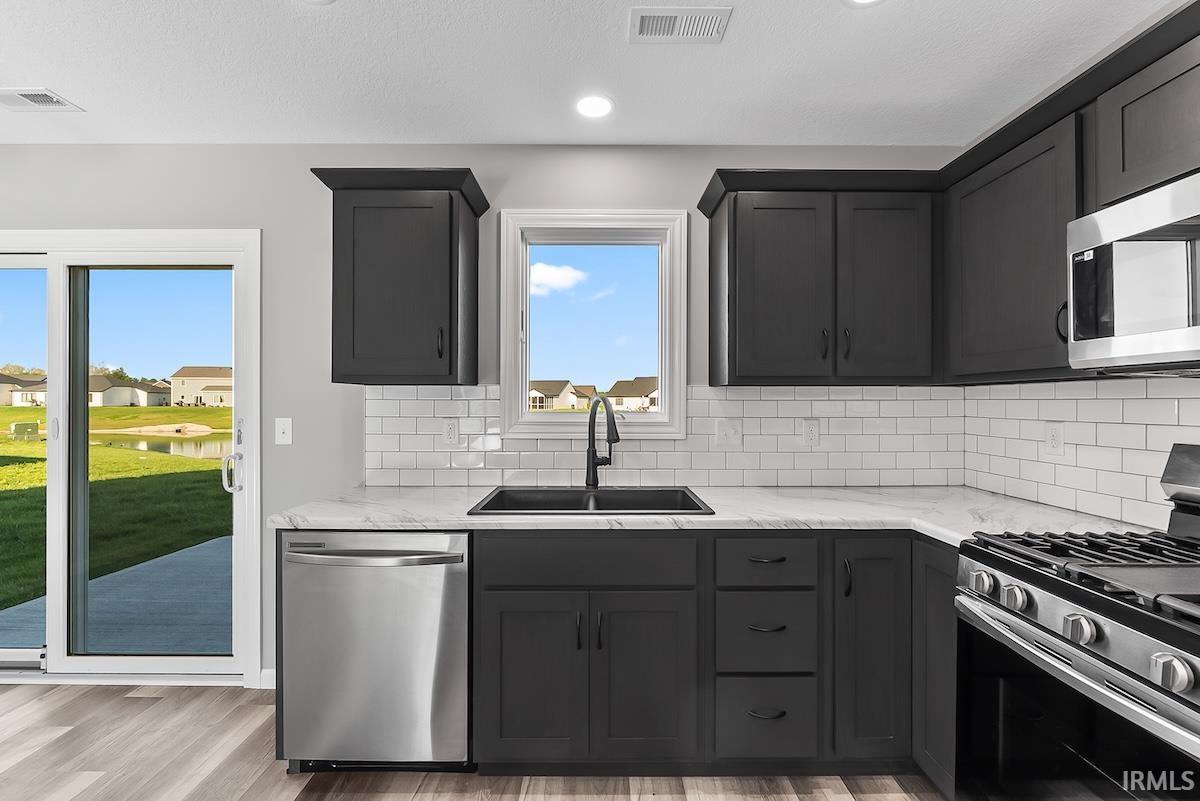 Kitchen featuring dark cabinetry, white subway tile backsplash, and light-toned countertops