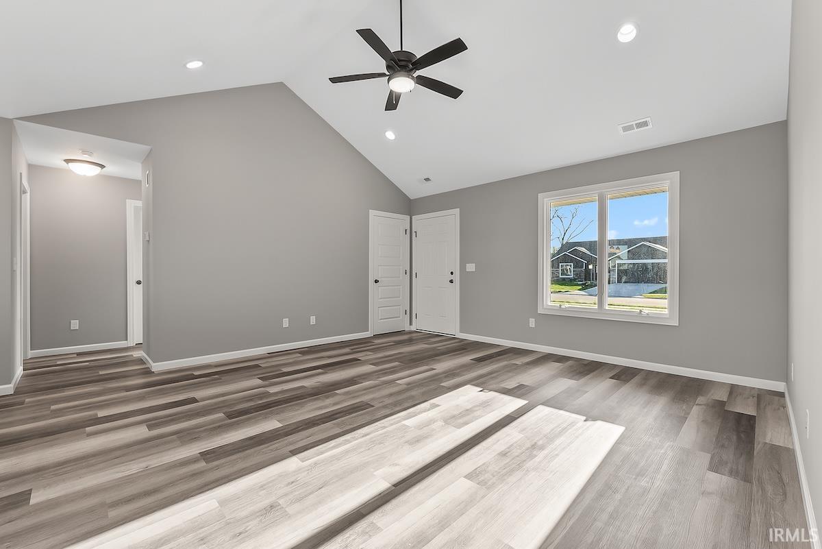 Spacious interior featuring a vaulted ceiling, wood-finish flooring, recessed lighting, and a ceiling fan