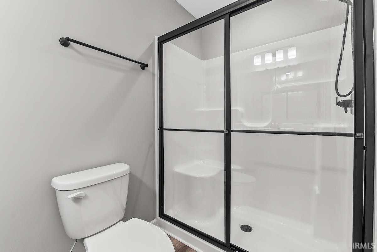Modern shower enclosure with black-framed glass doors and white shower surround