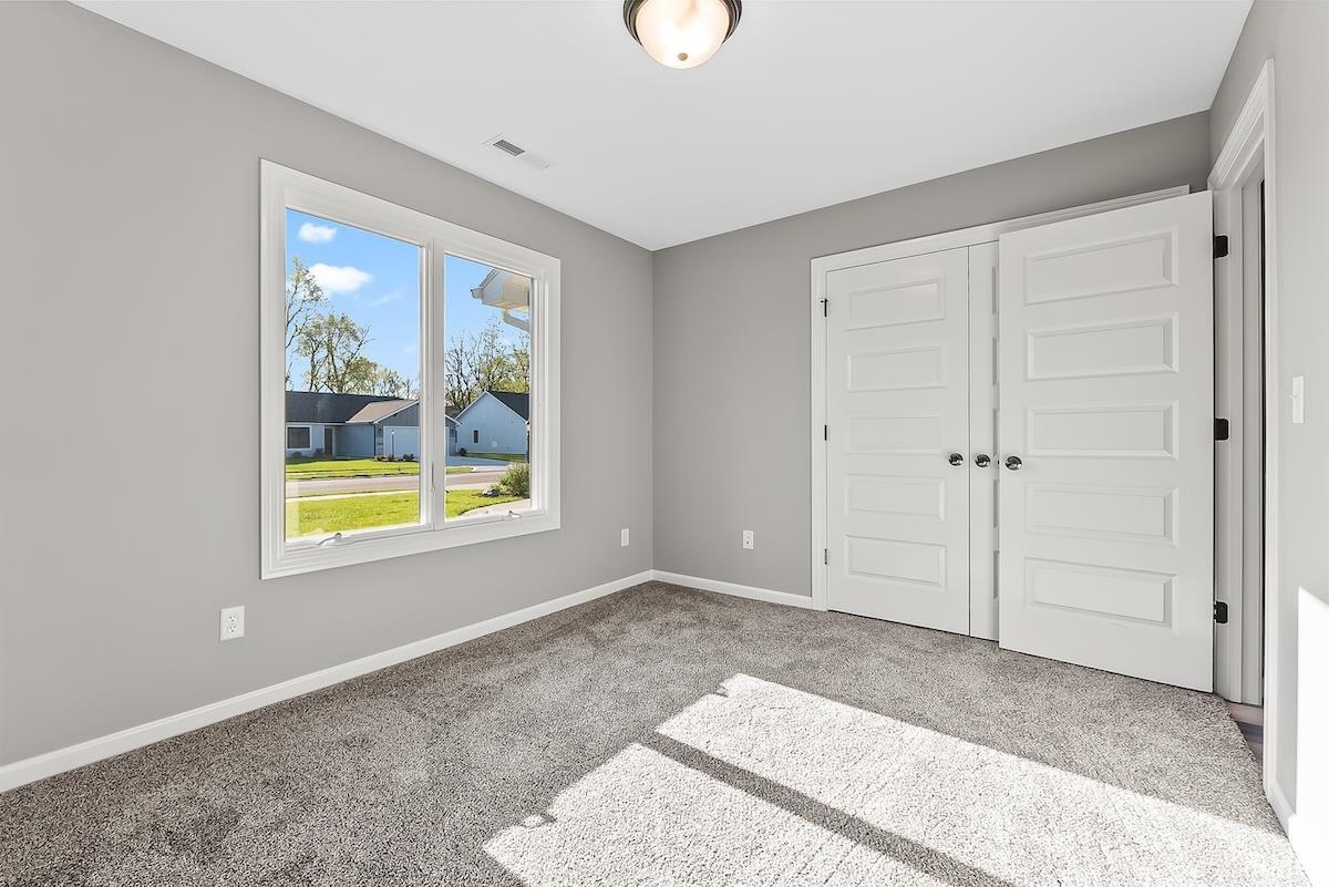 Bright room featuring a large window, plush gray carpet, light gray walls, and white trim