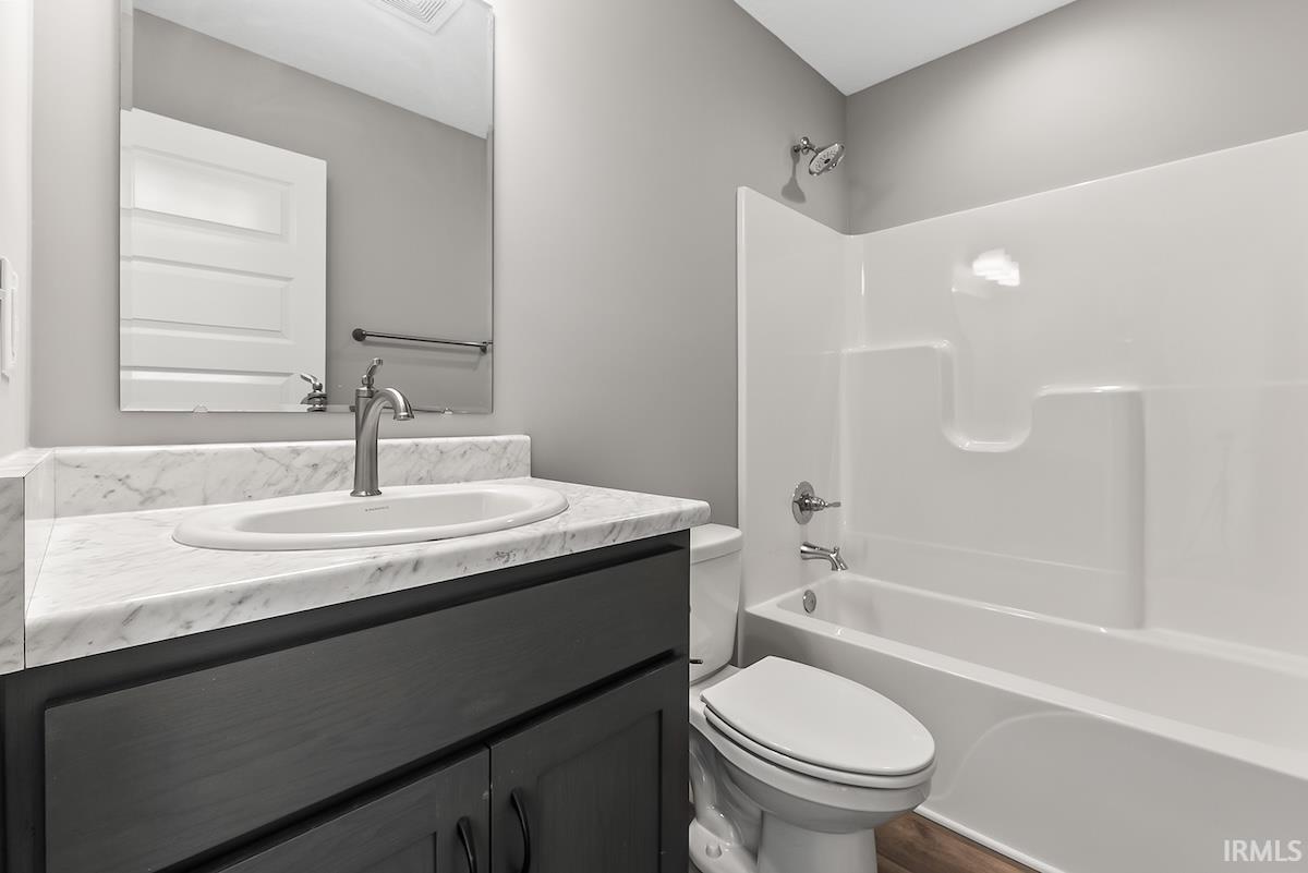 Bathroom featuring a dark wood-finish vanity with an undermount sink, a white marble-patterned countertop, and brushed nickel fixtures