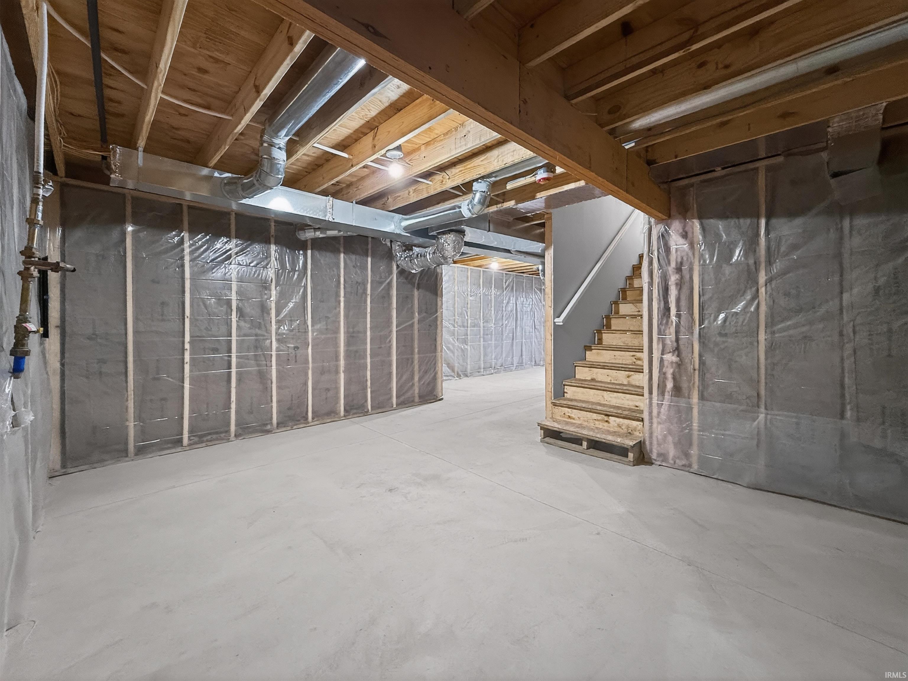 Unfinished lower level with exposed wooden joists and concrete flooring