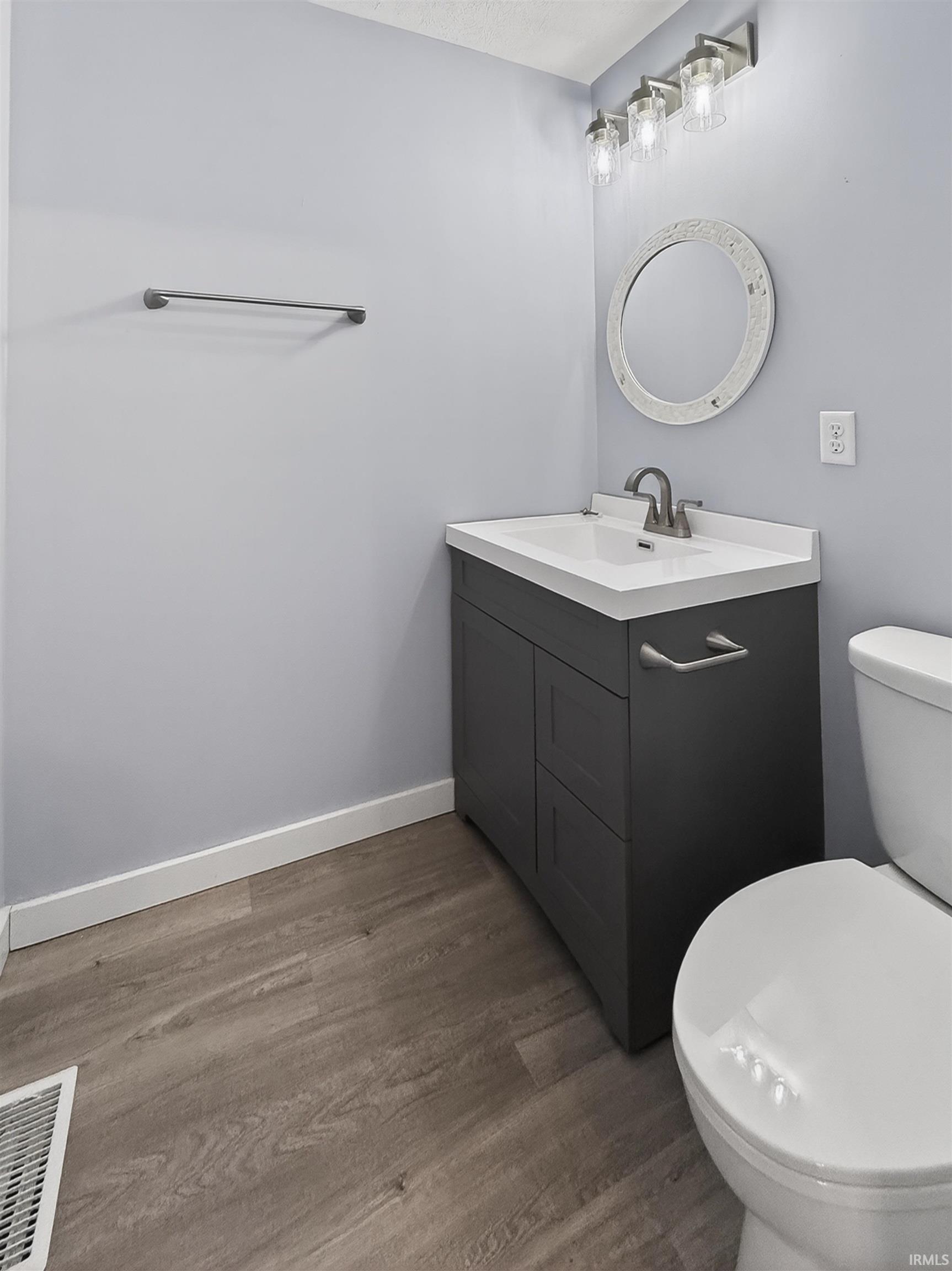 Bathroom featuring a dark gray vanity with integrated sink, brushed nickel faucet, and a round decorative mirror