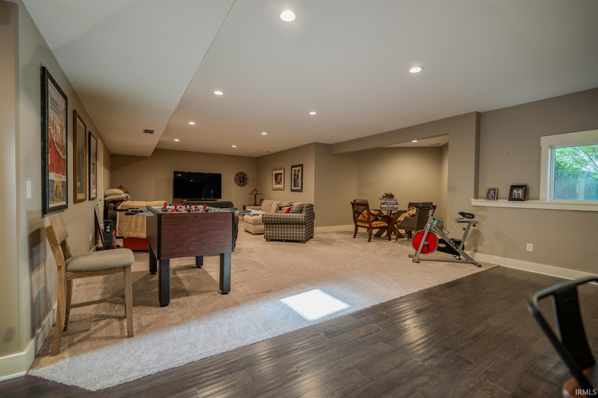 Spacious lower-level area featuring recessed lighting, a window, and two distinct flooring types