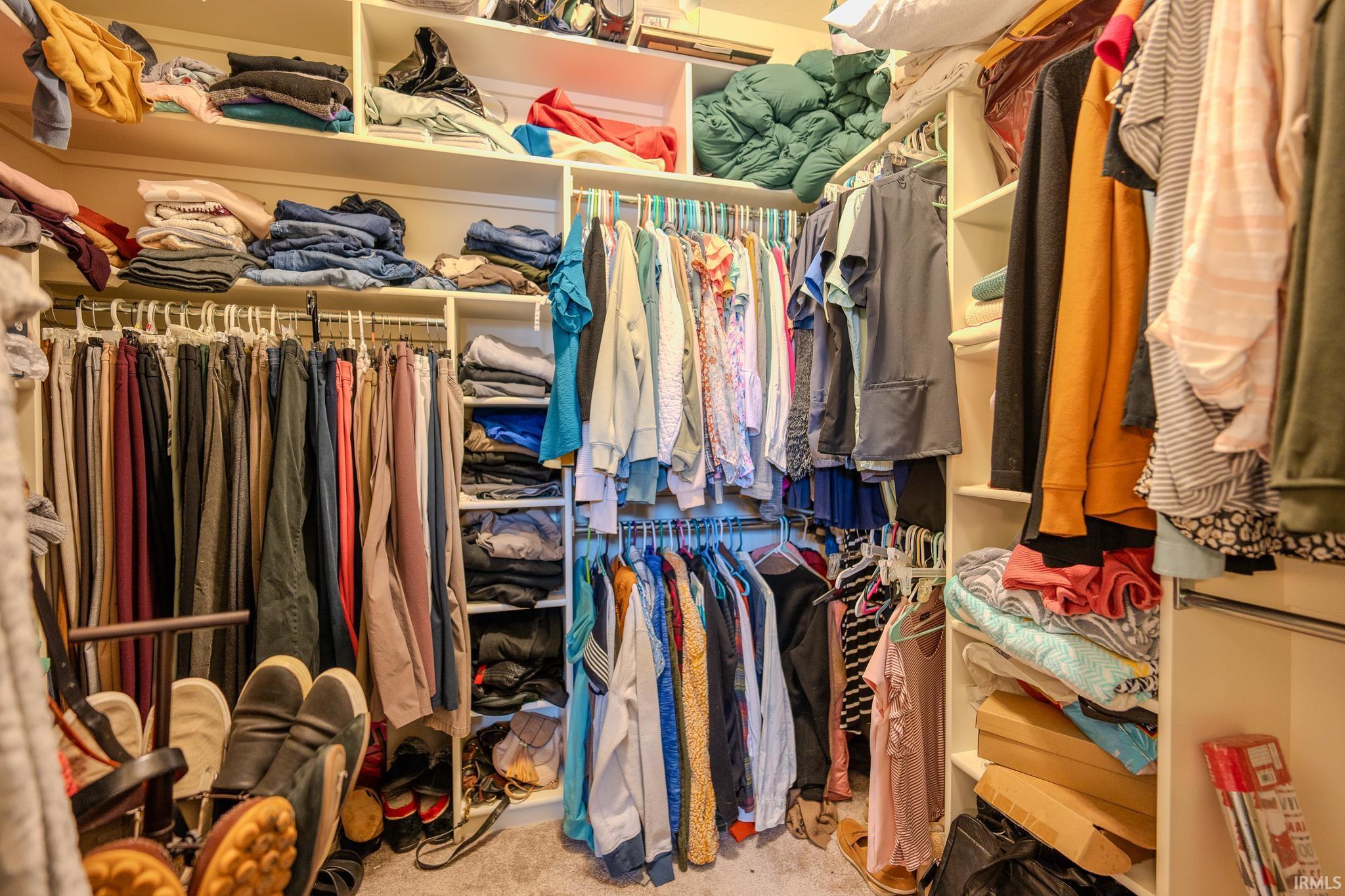 Built-in closet system featuring multiple hanging rods, integrated shelving, and carpet flooring