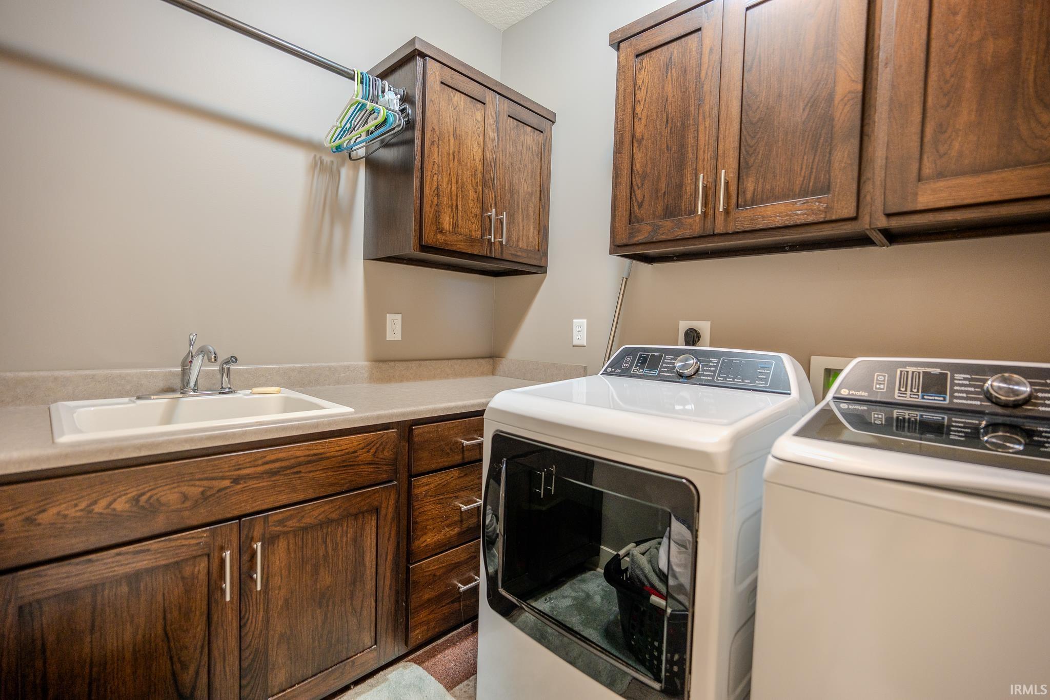 Utility room featuring dark wood-finish cabinetry, a utility sink with a chrome faucet, and a countertop