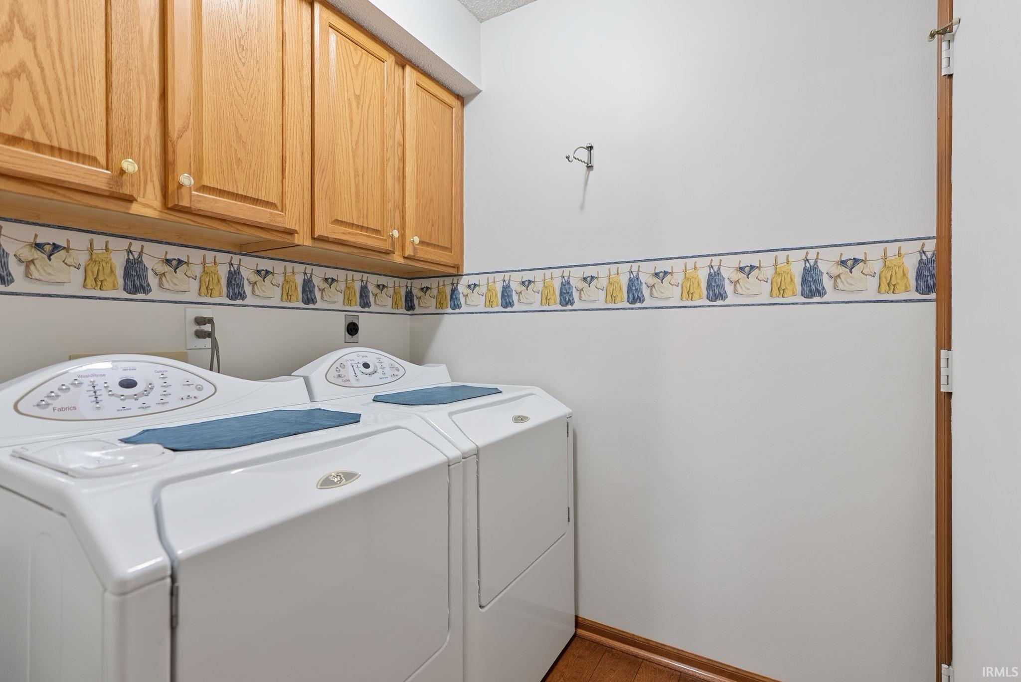 Utility area with hardwood flooring and upper wood cabinetry