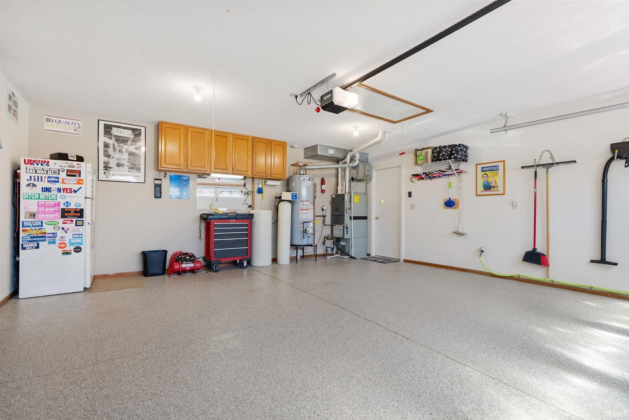 Spacious garage featuring a speckled epoxy floor coating, light beige walls, and overhead lighting