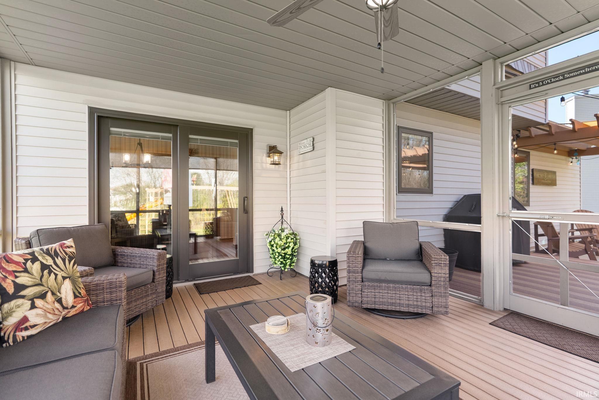 Screened porch featuring a ceiling fan, light-toned composite decking, and white siding