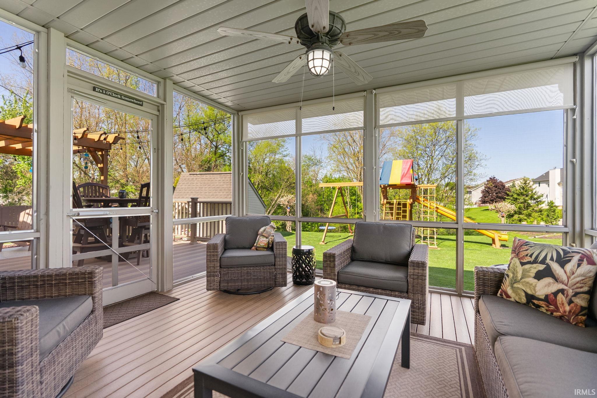 Screened porch with wood-finish flooring and a ceiling fan with integrated lighting