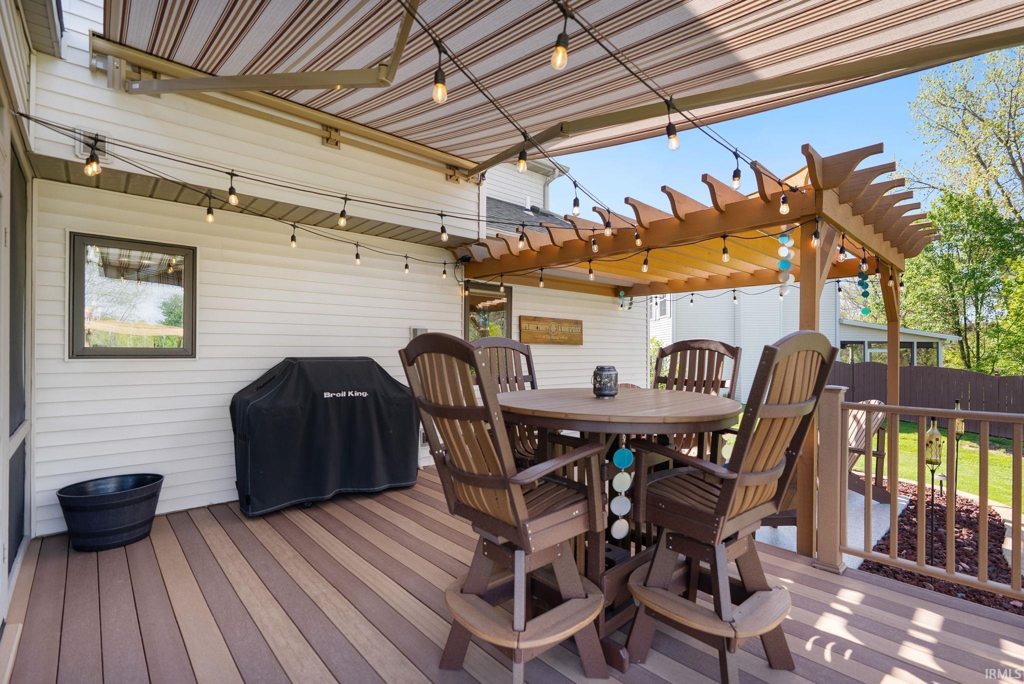 Expansive outdoor deck featuring two-tone composite decking, a retractable awning, and an attached pergola