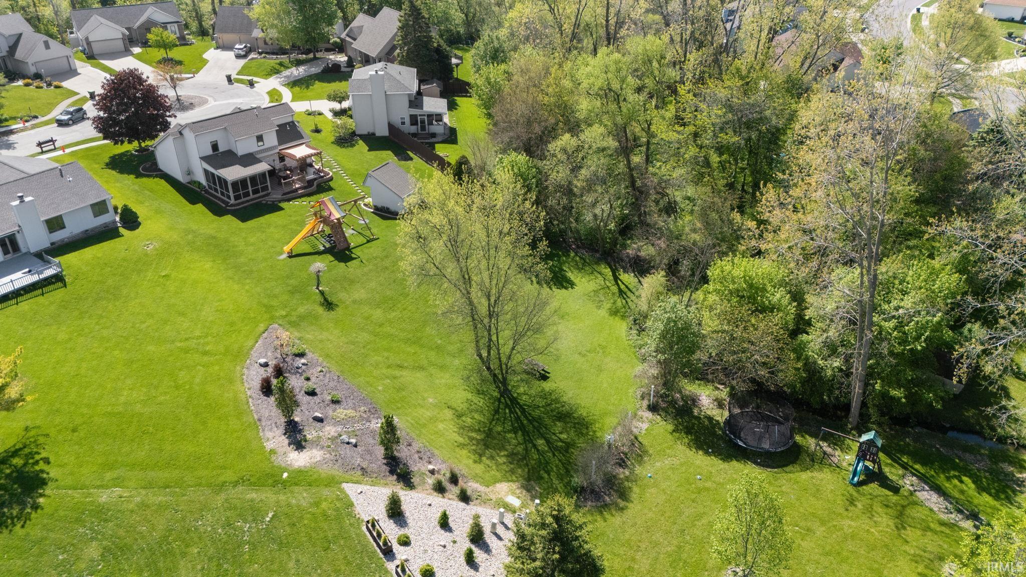 Expansive green space featuring a sloped lawn, mature trees, and landscaping elements