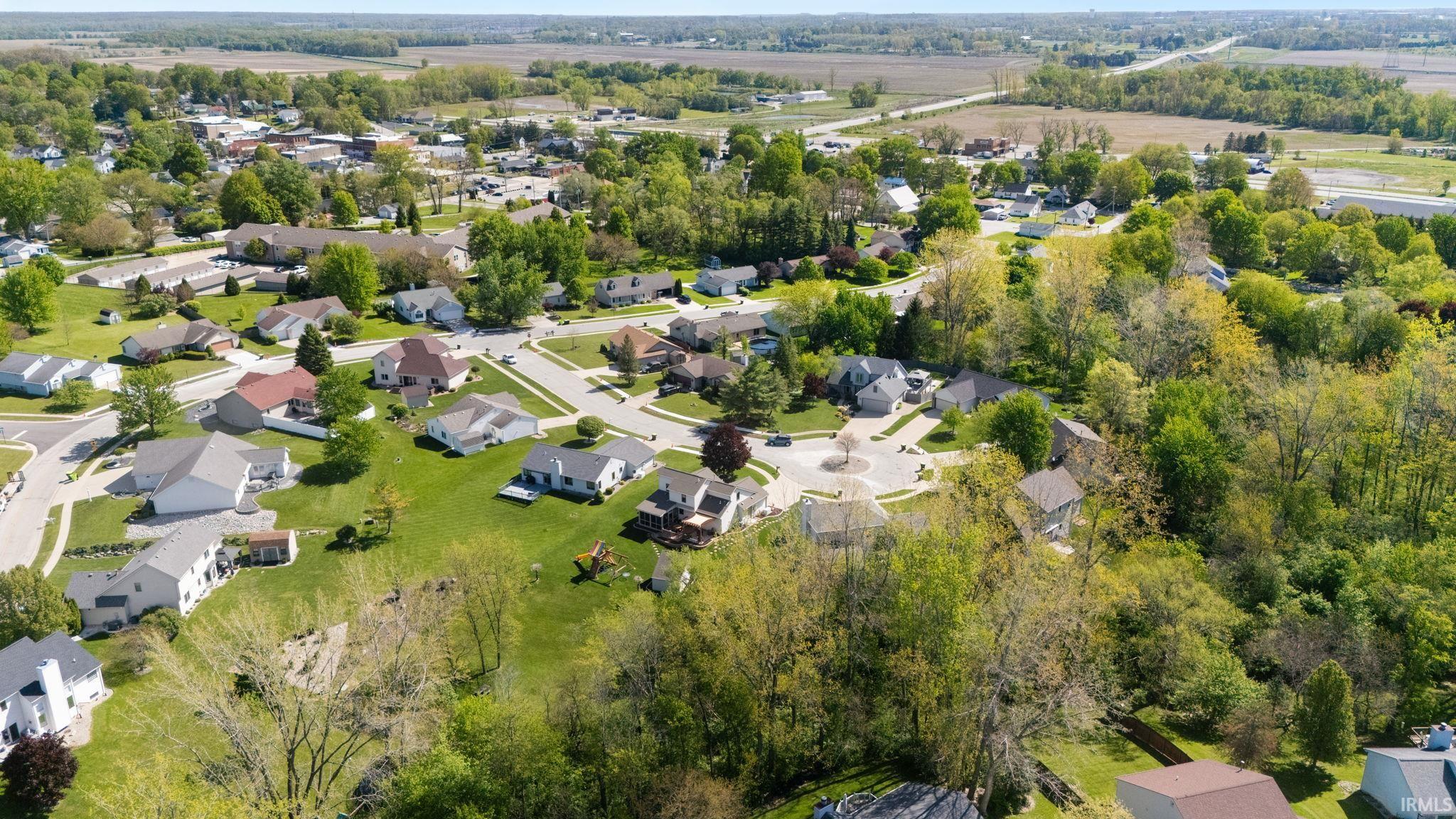 Residential community featuring a variety of single-family homes, mature trees, green lawns, and paved roads