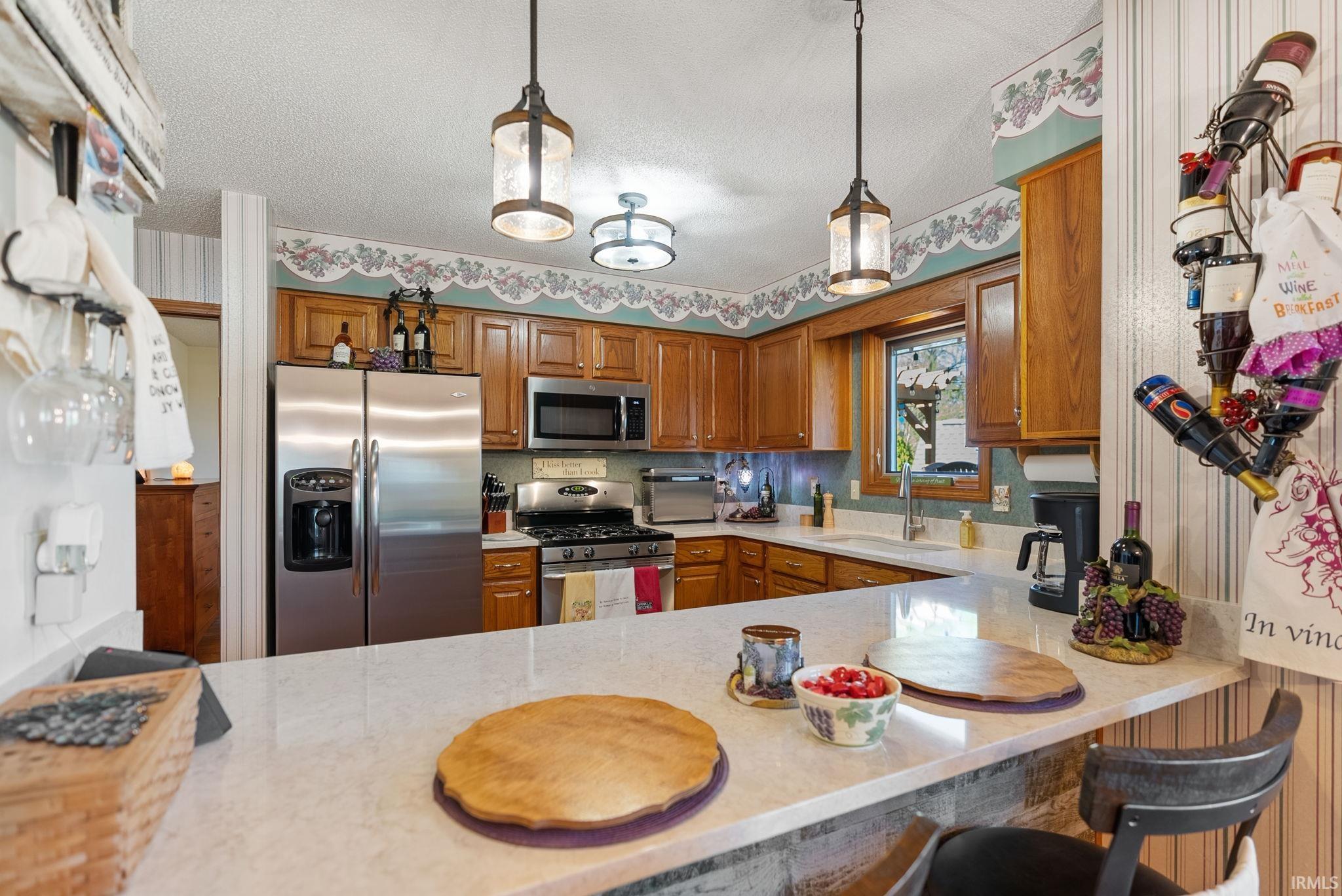 Kitchen featuring a breakfast bar with stone-finish countertop, stainless steel appliances, wood cabinetry, and recessed lighting