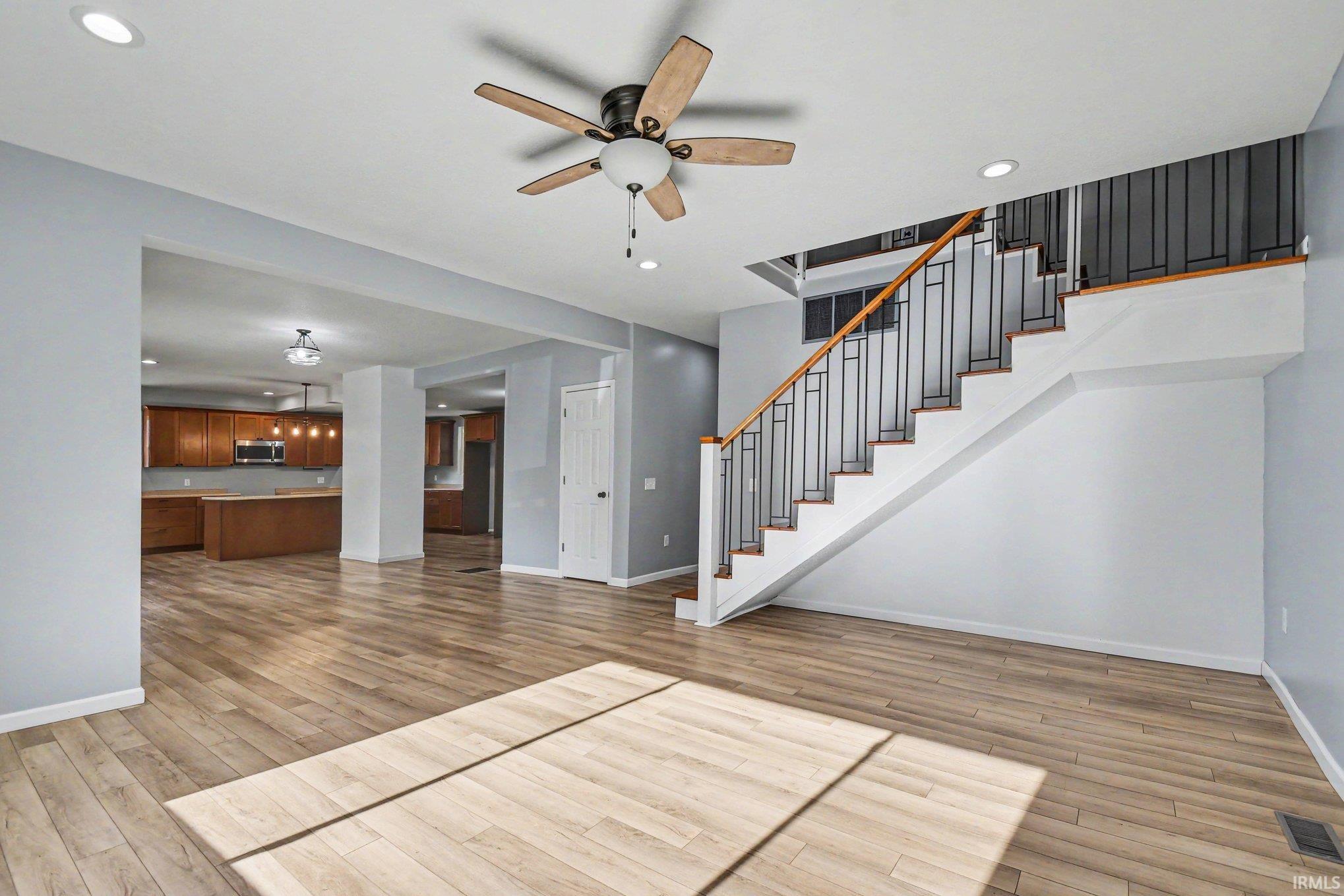 Spacious living area featuring wood-finish flooring, recessed lighting, and a ceiling fan
