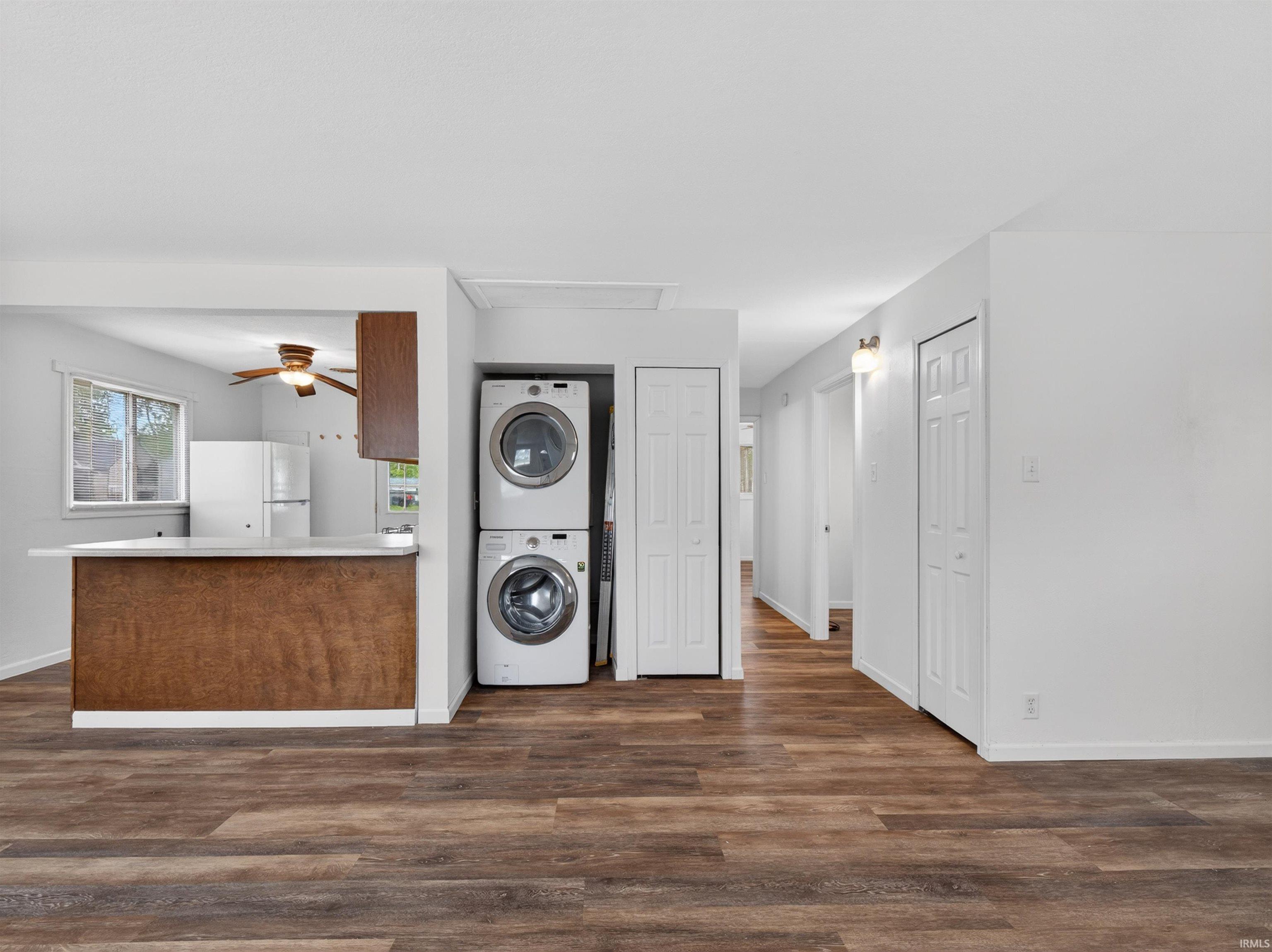 Open-concept living space featuring wood-finish flooring, a breakfast bar with a light-toned countertop, and a kitchen with a ceiling fan