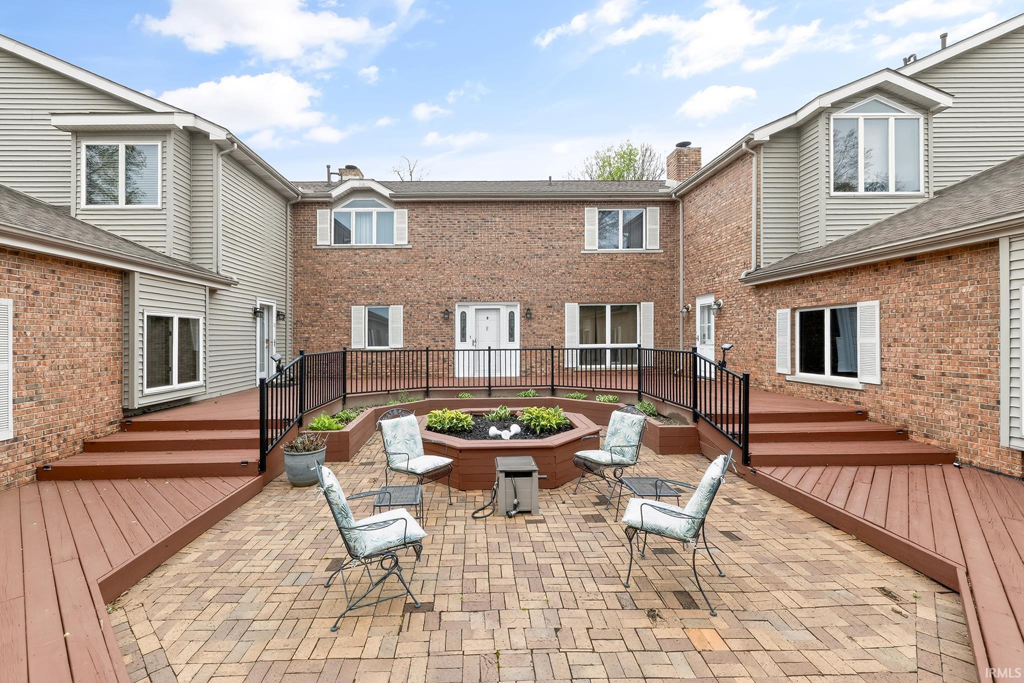 Exterior patio featuring brick pavers, a built-in planter, and two raised wood-finish decks