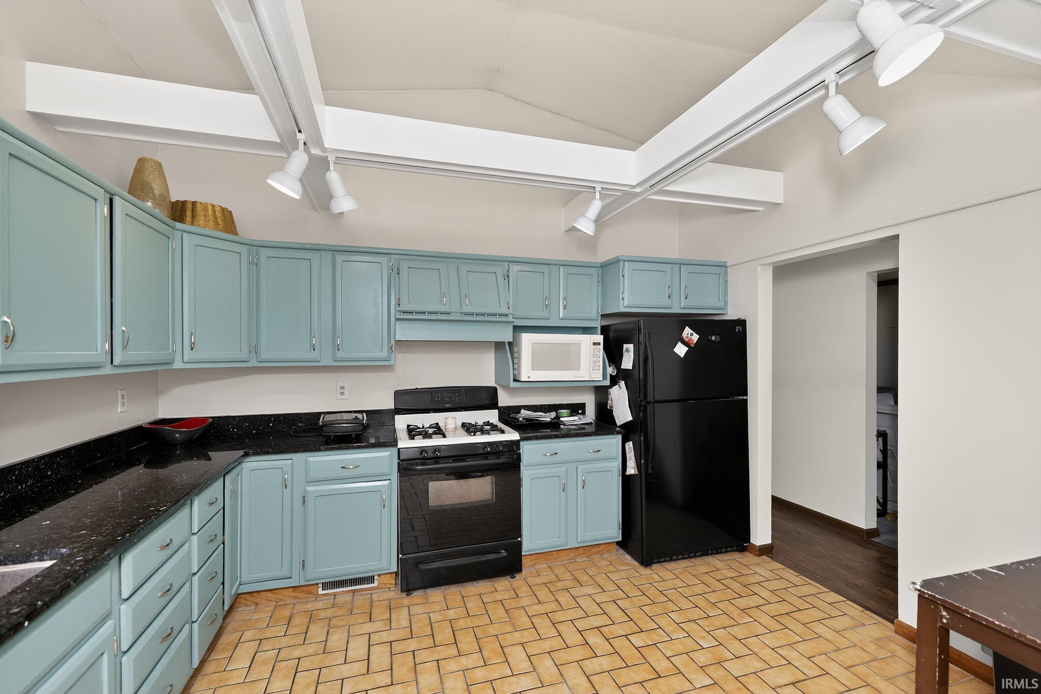 Kitchen featuring blue cabinetry with dark countertops, a black gas range, and a black refrigerator