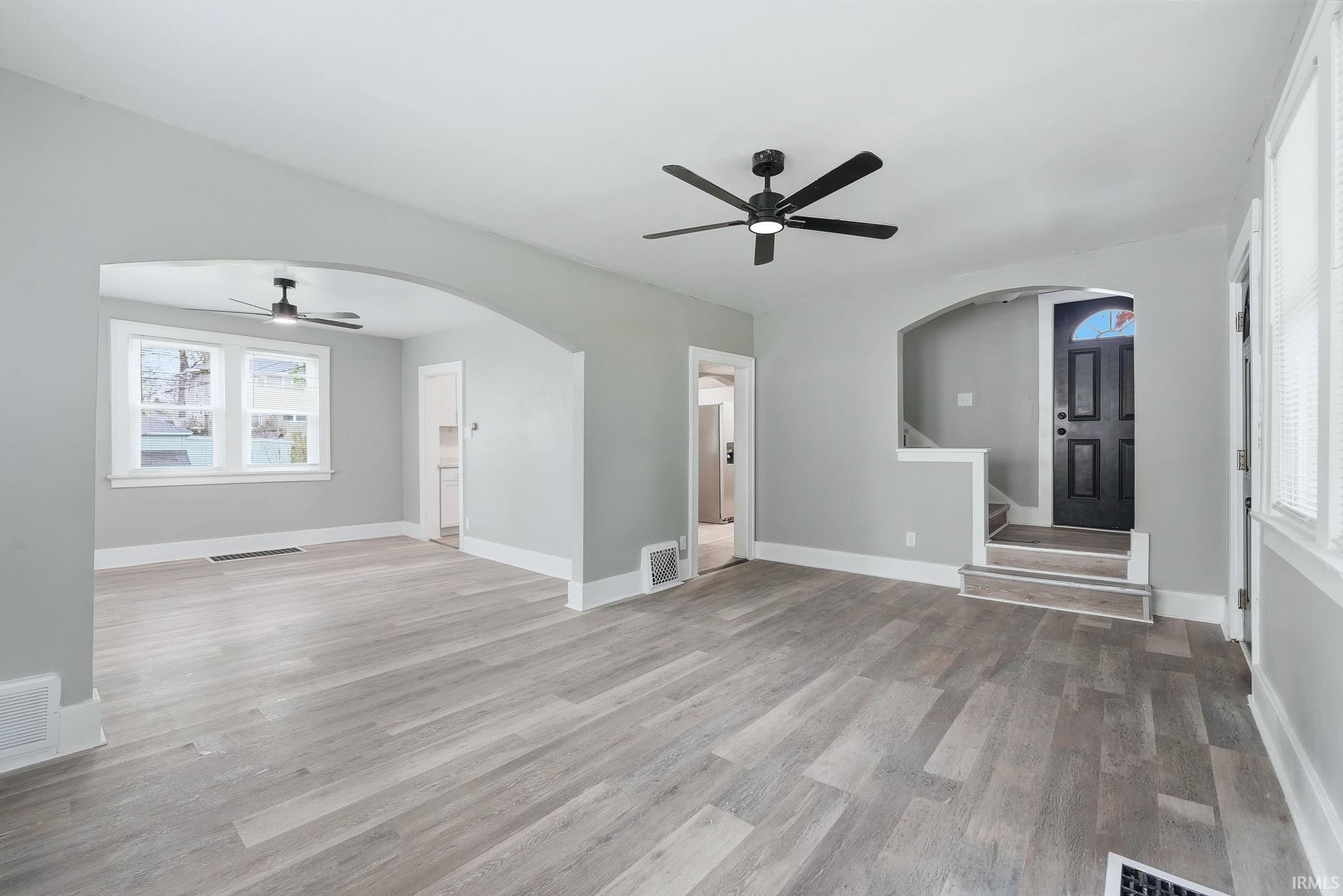 Spacious living area featuring wood-finish flooring throughout, light gray wall paint, and white trim