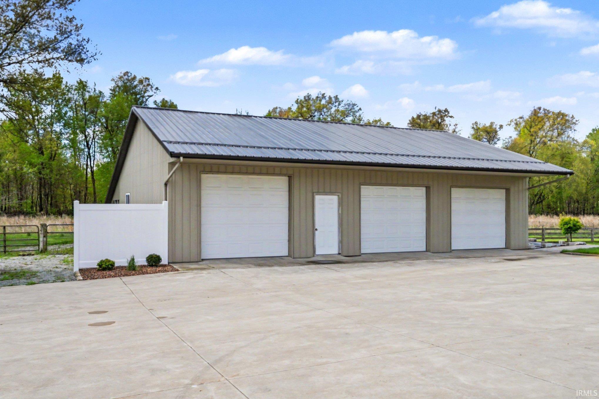 Three-bay barn building with a gray metal roof and featuring three garage doors and