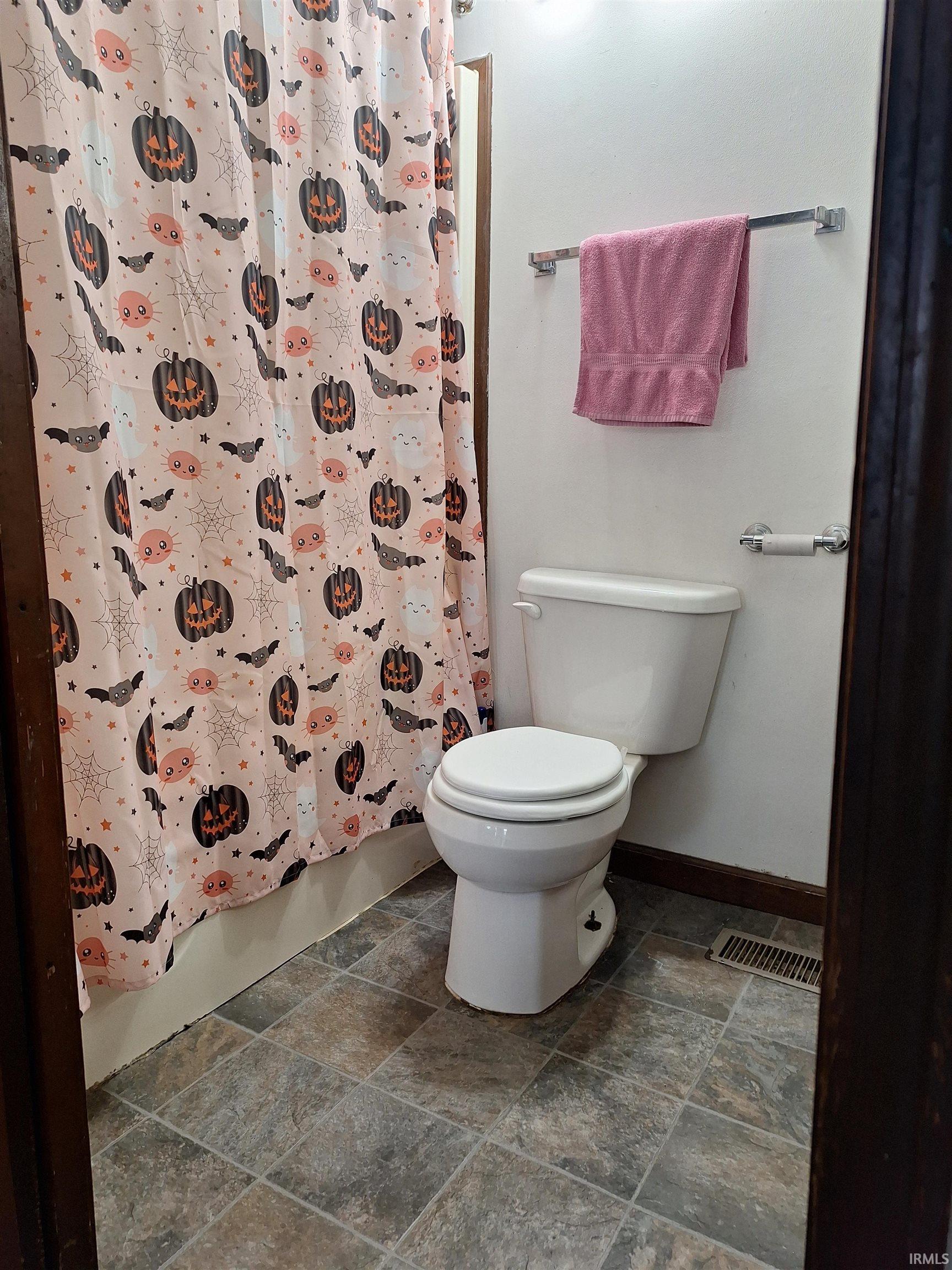 Bathroom featuring a white toilet, tile-look flooring, and a chrome towel bar