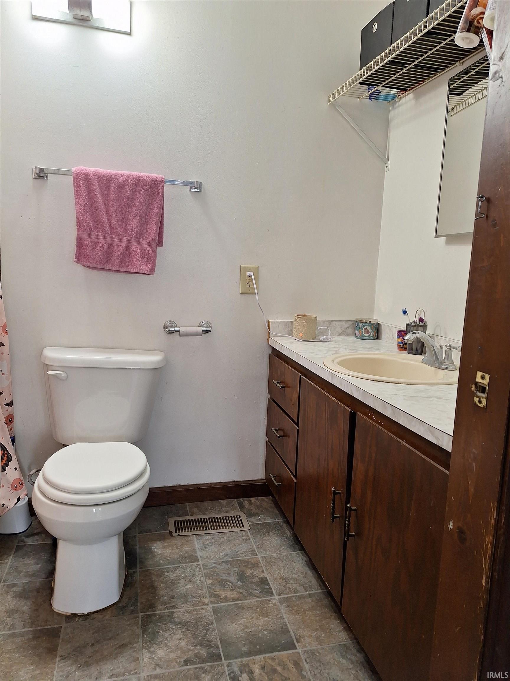 Bathroom featuring a vanity with dark wood-finish cabinetry, a drop-in sink, and a laminate countertop