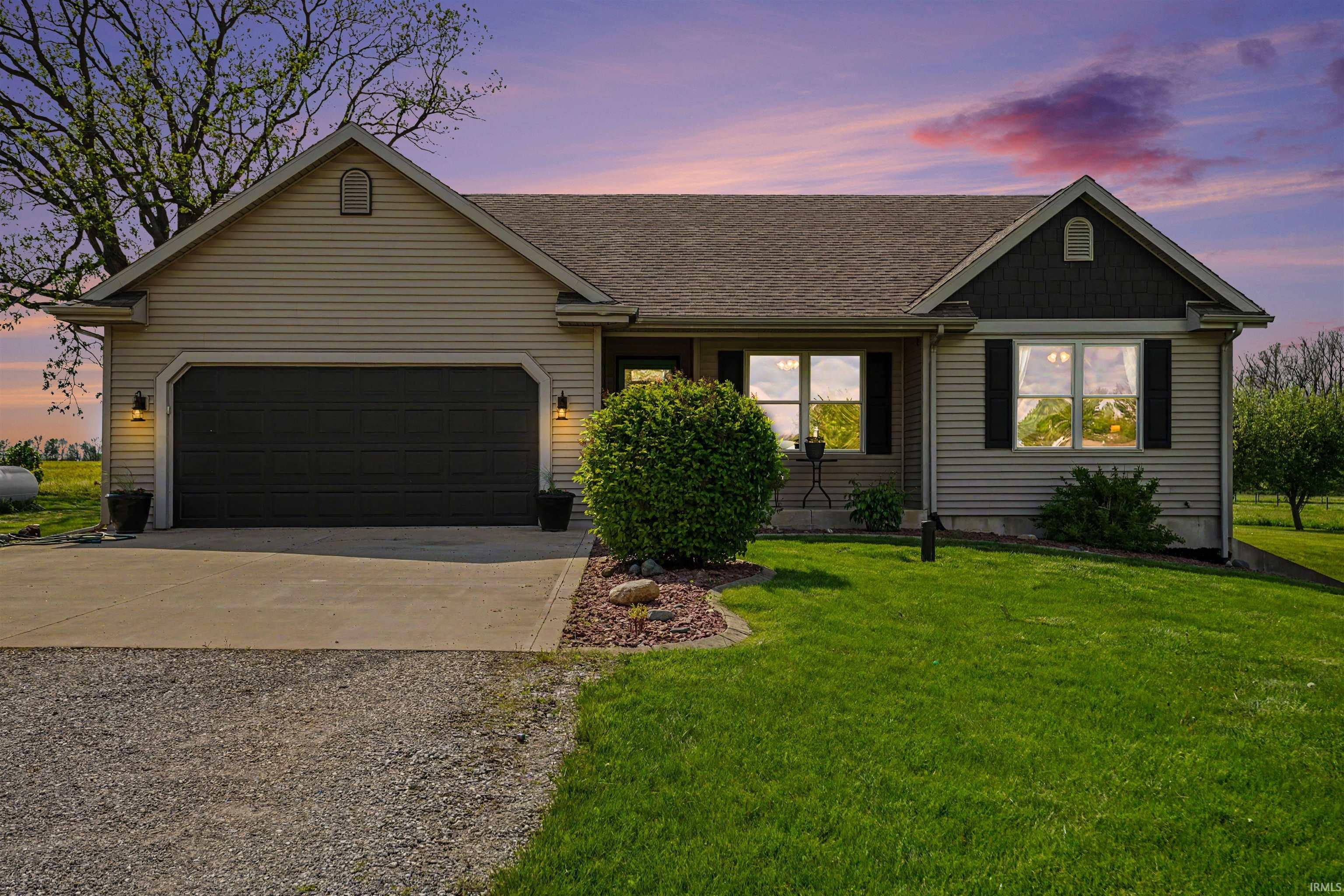 Ranch-style residence featuring light-toned horizontal siding, a dark roof, and a two-car garage with a dark door