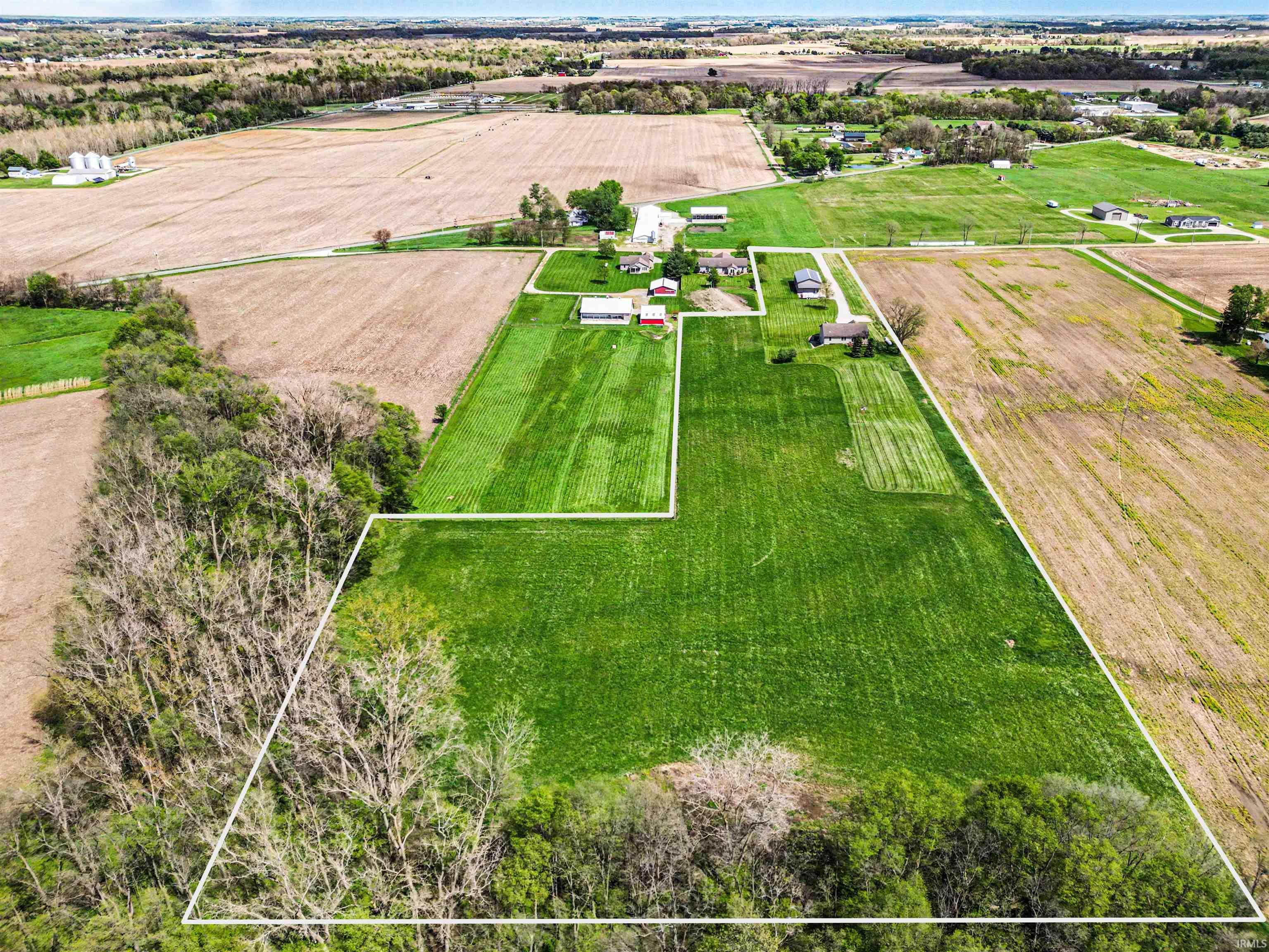 Expansive rural property featuring substantial acreage, a mixture of cleared land and mature tree lines, and multiple structures