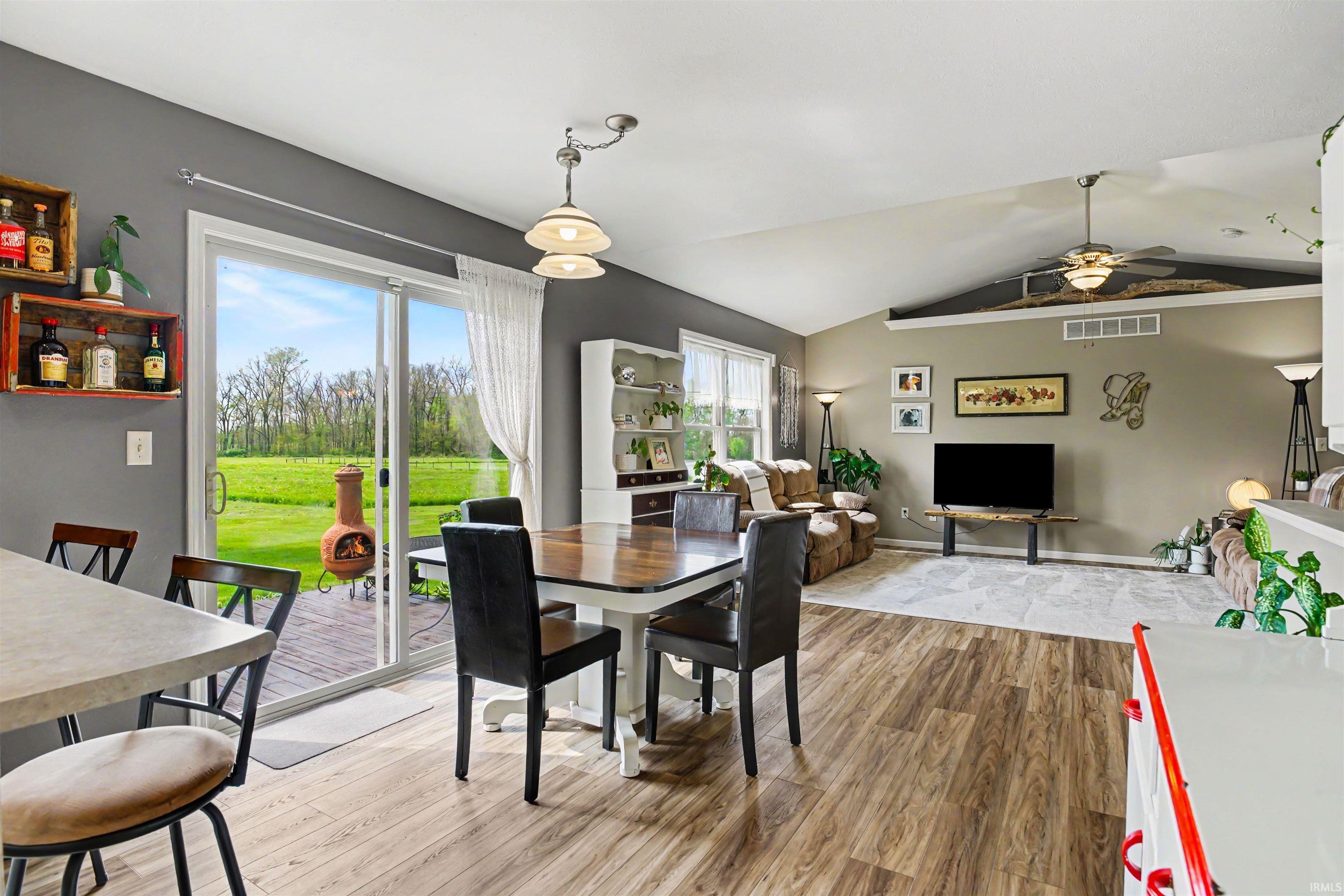 Open-concept living area featuring wood-finish flooring, a vaulted ceiling, and a ceiling fan