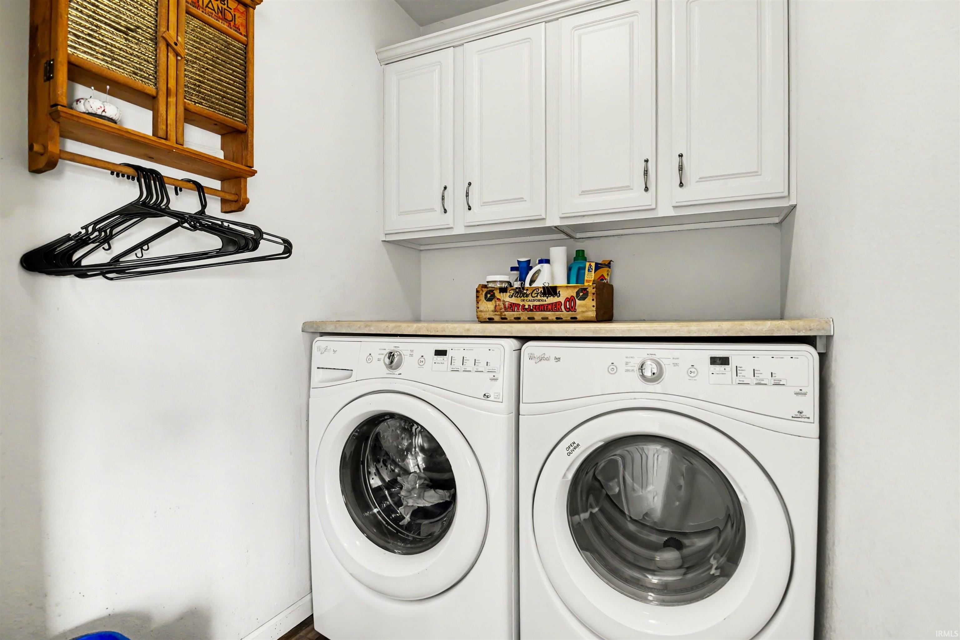 Functional laundry area featuring white upper cabinetry with brushed nickel hardware, a light-toned countertop, and light wall finishes