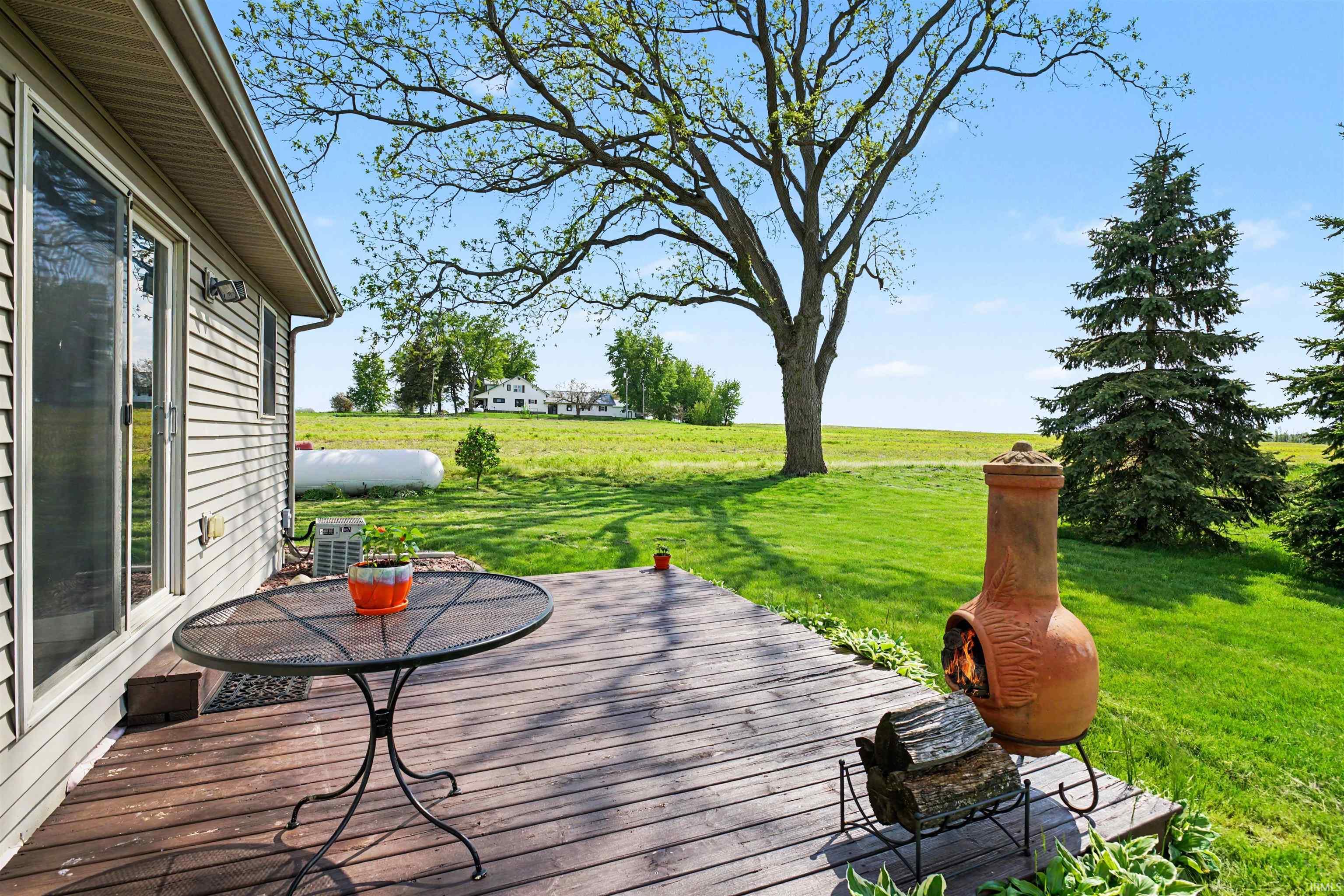 Expansive wooden deck with a sliding glass door entry and green landscape