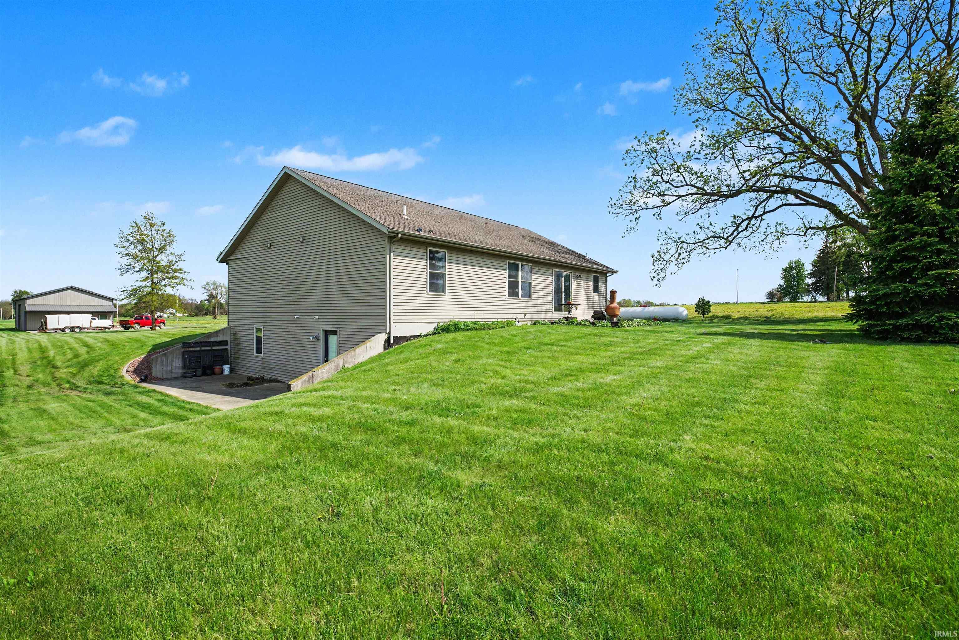 Split-level residence featuring beige vinyl siding and a dark shingle roof