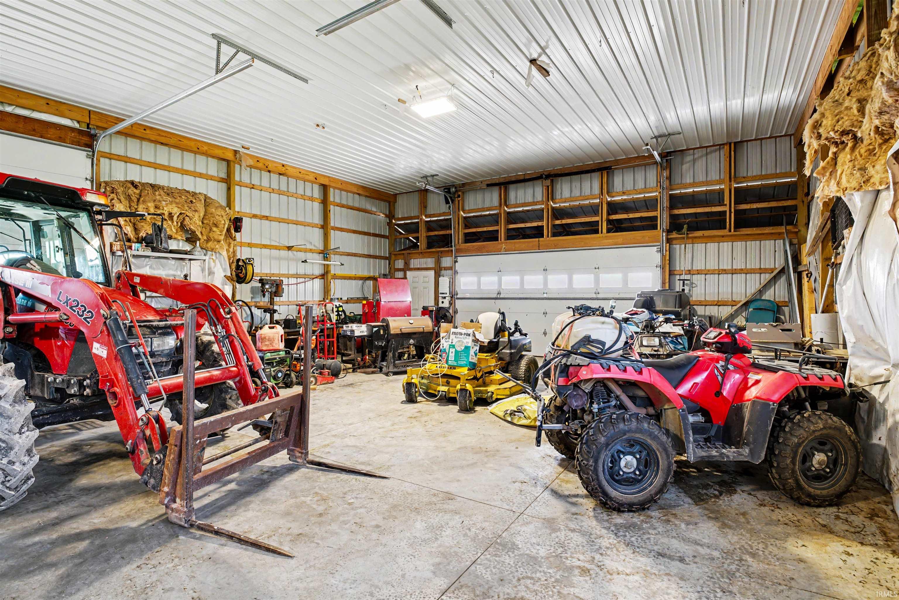 Spacious outbuilding featuring a corrugated metal ceiling, concrete flooring, and multiple garage doors