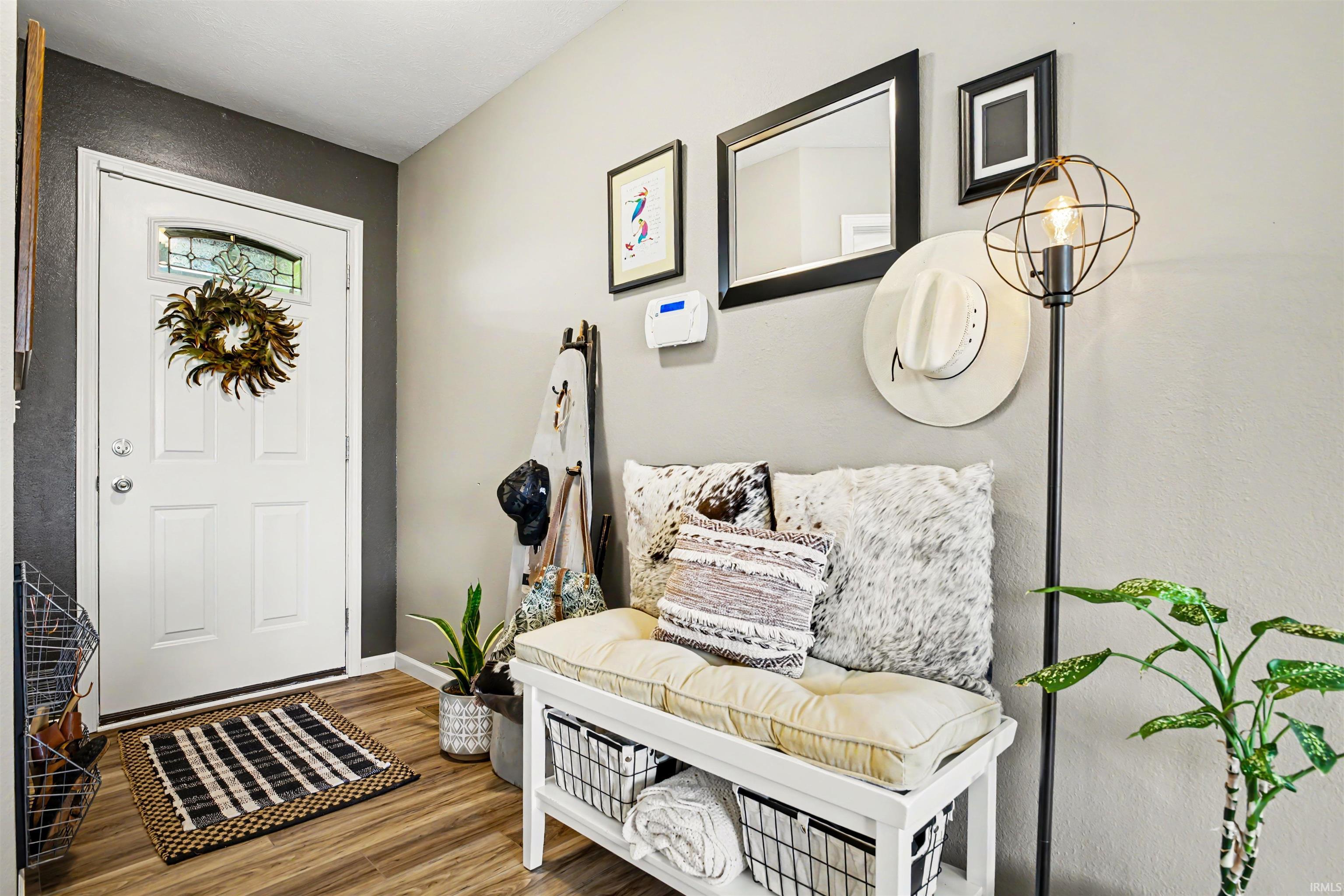 Entryway featuring wood-finish flooring, a white paneled door with decorative glass insert, and a built-in storage bench