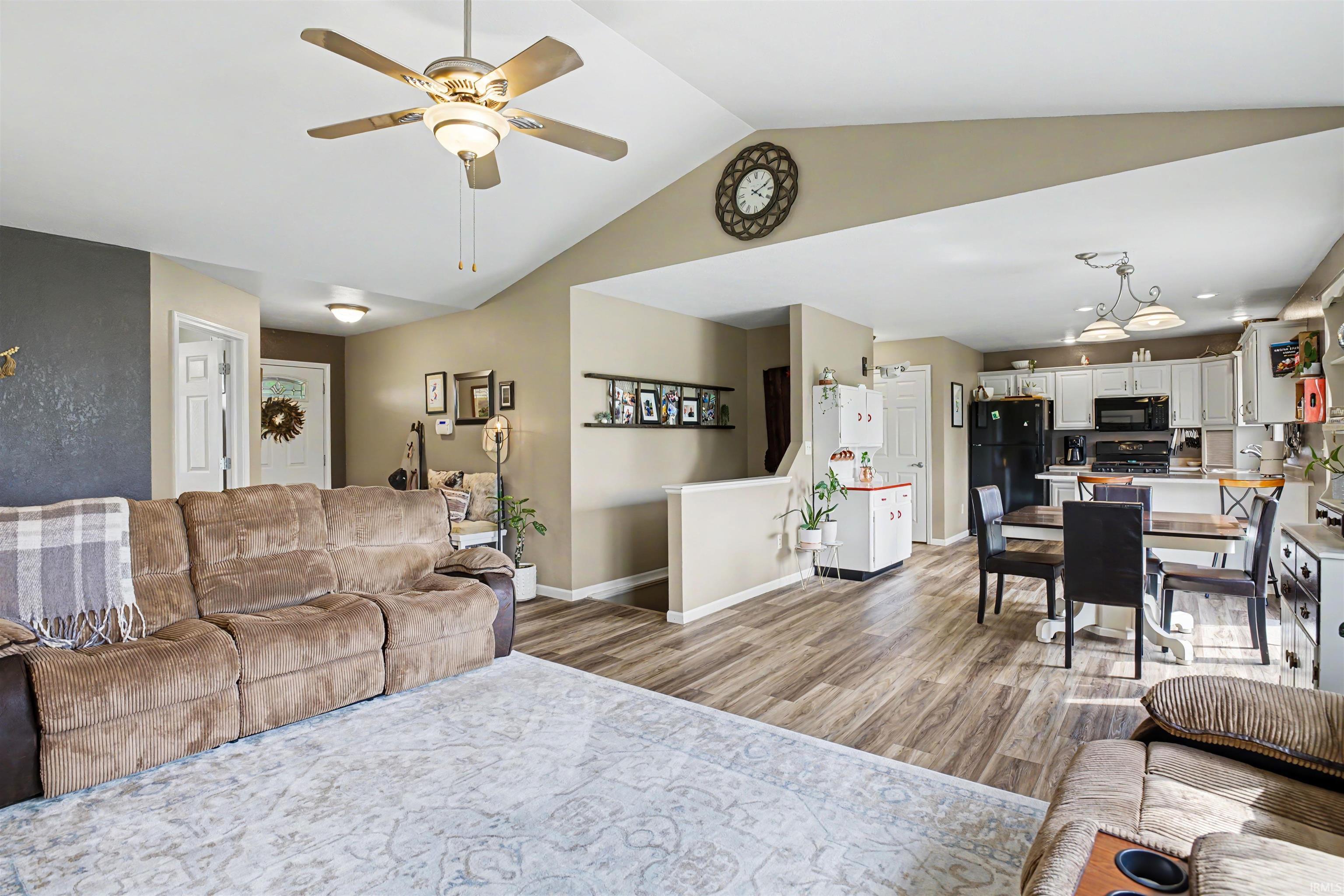 Vaulted ceilings define this open-concept living space, featuring wood-finish flooring throughout the main areas
