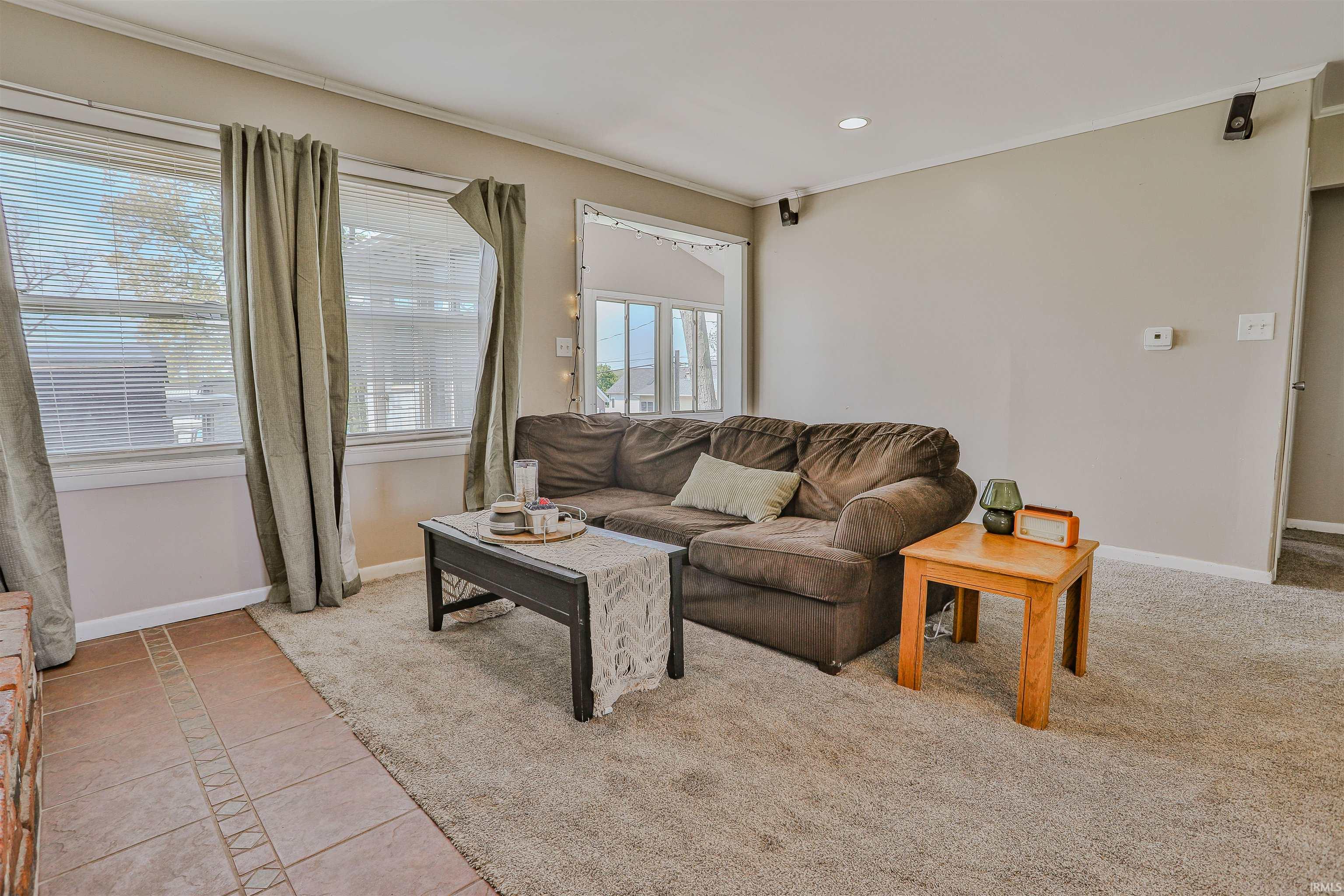 Living area featuring neutral wall tones, carpet flooring, multiple windows with blinds, and recessed lighting