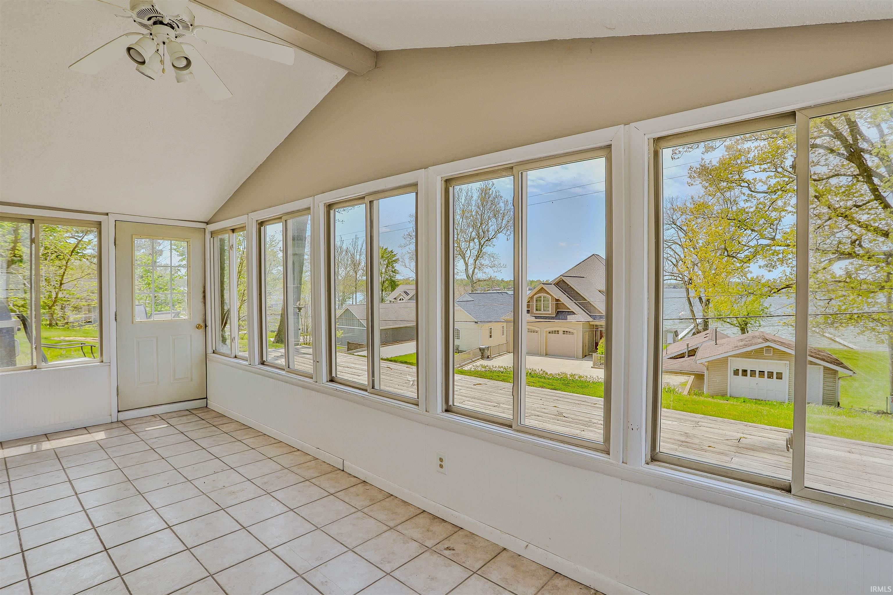 Sunroom featuring an angled ceiling, a ceiling fan, and tiled flooring