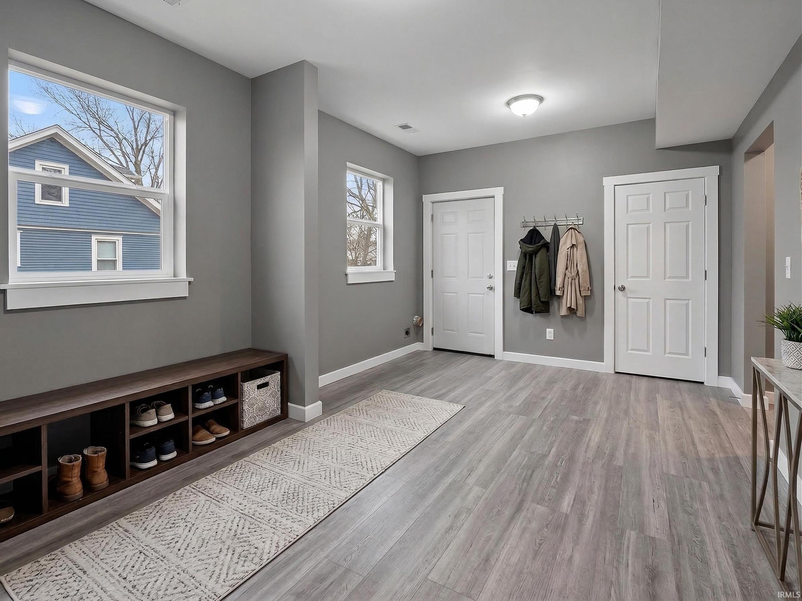 Entry area featuring wood-finish flooring, light gray wall tones, and a built-in shoe storage bench