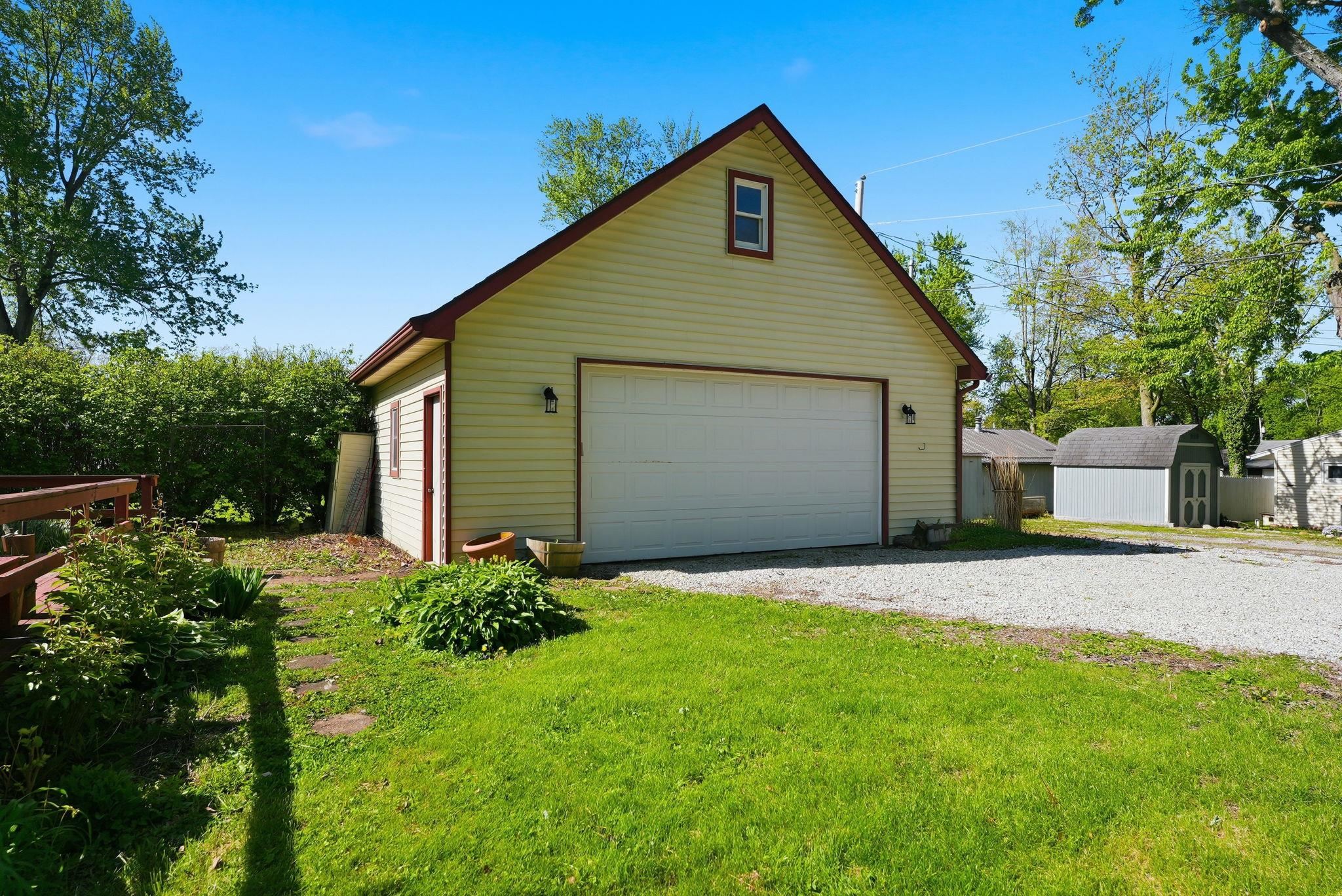 Detached garage with light-colored siding, a white overhead door, and an upper gable window
