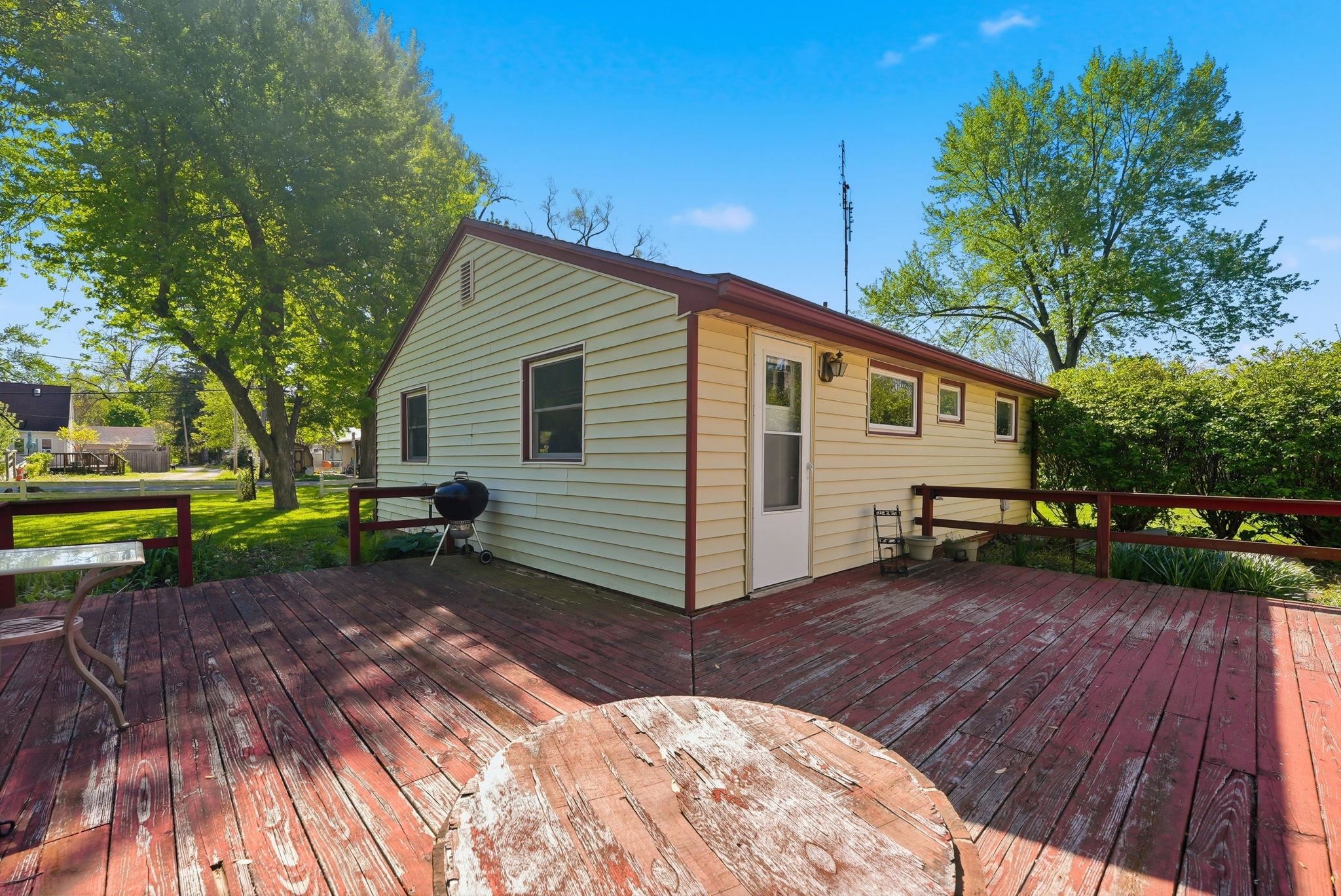 Expansive wood deck with painted red railing, featuring direct access to the siding-clad structure